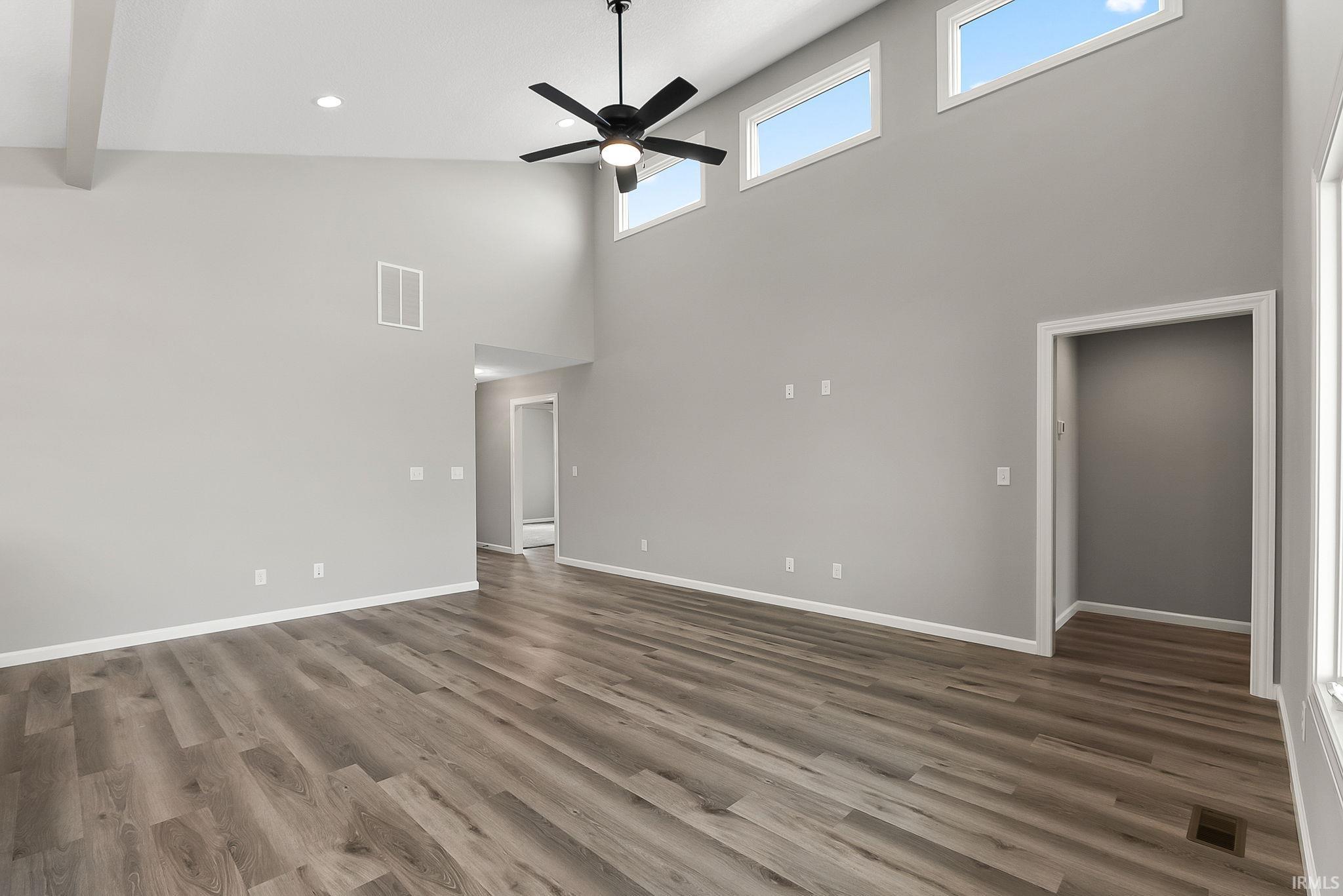 Unfurnished living room with ceiling fan, dark wood-style floors, a high ceiling, and recessed lighting