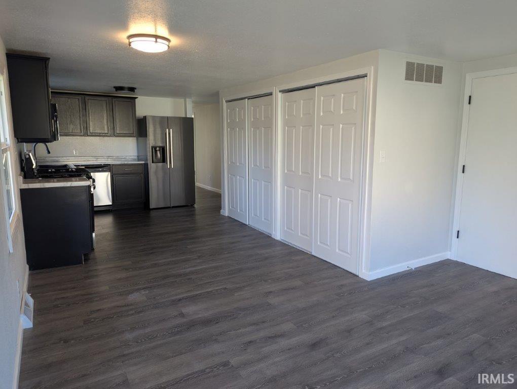 Kitchen featuring stainless steel appliances, light countertops, dark wood finished floors, and open floor plan