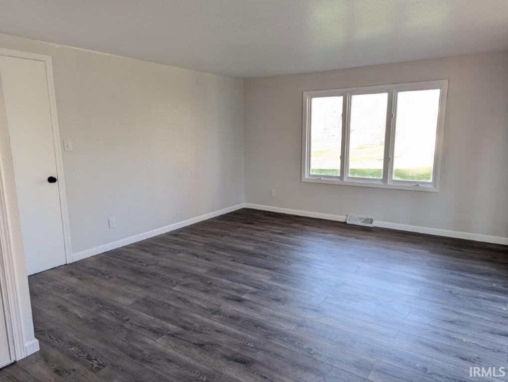 Unfurnished room with dark wood-style floors and baseboards
