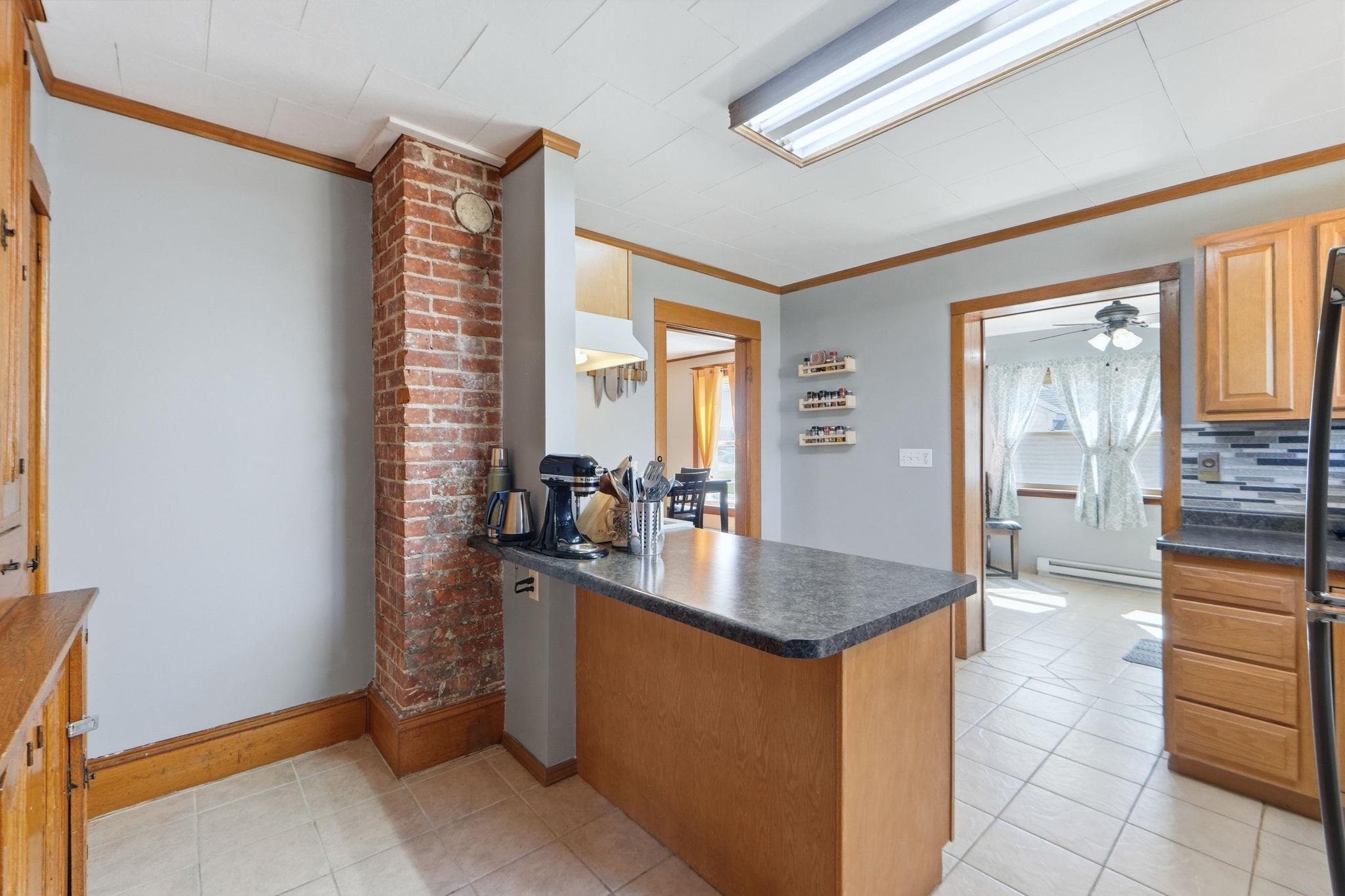Kitchen featuring dark countertops, crown molding, a peninsula, light tile patterned floors, and wood finish cabinetry