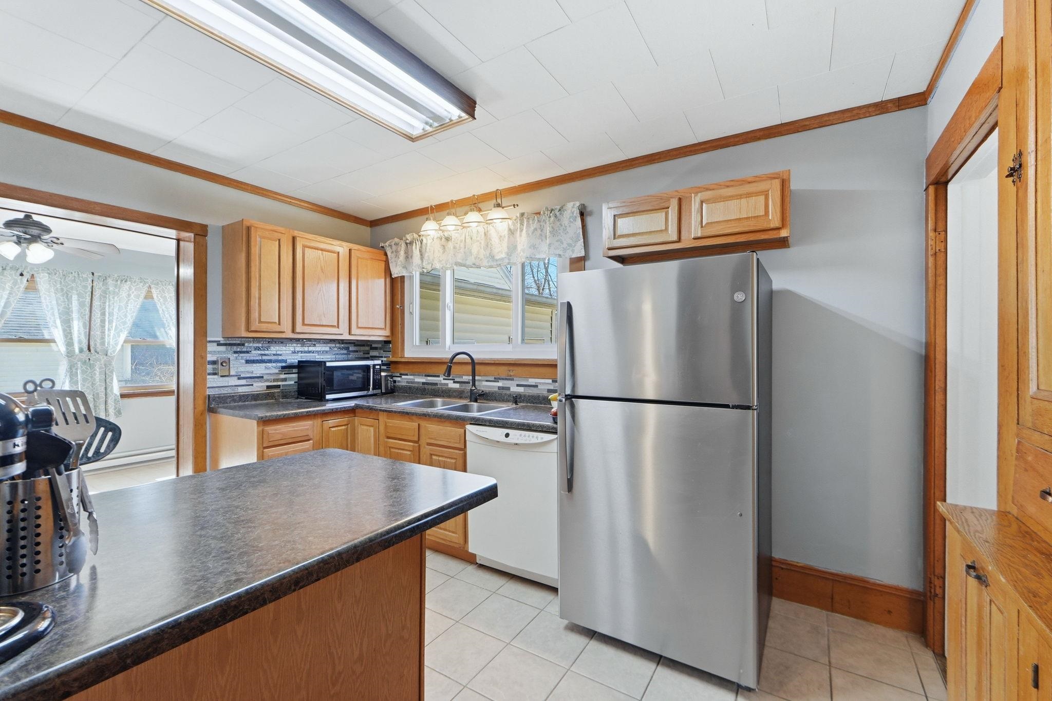 Kitchen featuring stainless steel appliances, ornamental molding, ceiling fan, dark countertops, and backsplash