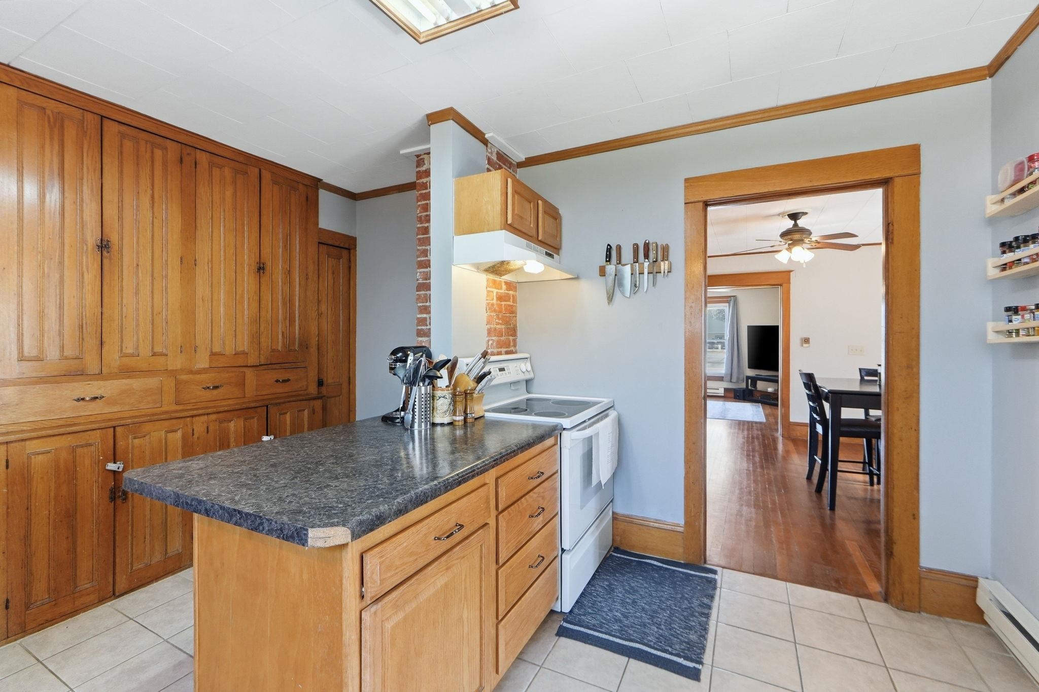 Kitchen with white electric range, dark countertops, ceiling fan, wood finish cabinetry, and crown molding