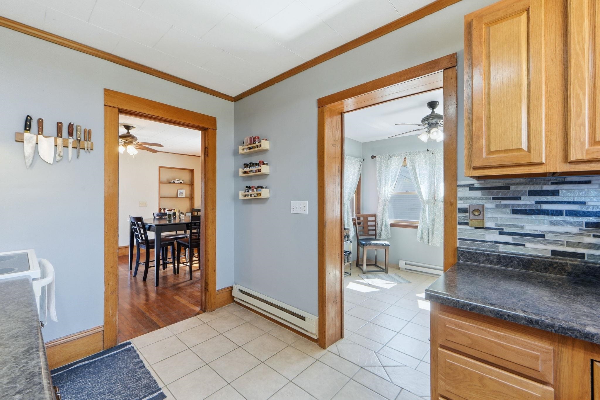 Kitchen featuring a ceiling fan, light tile patterned floors, dark countertops, and crown molding