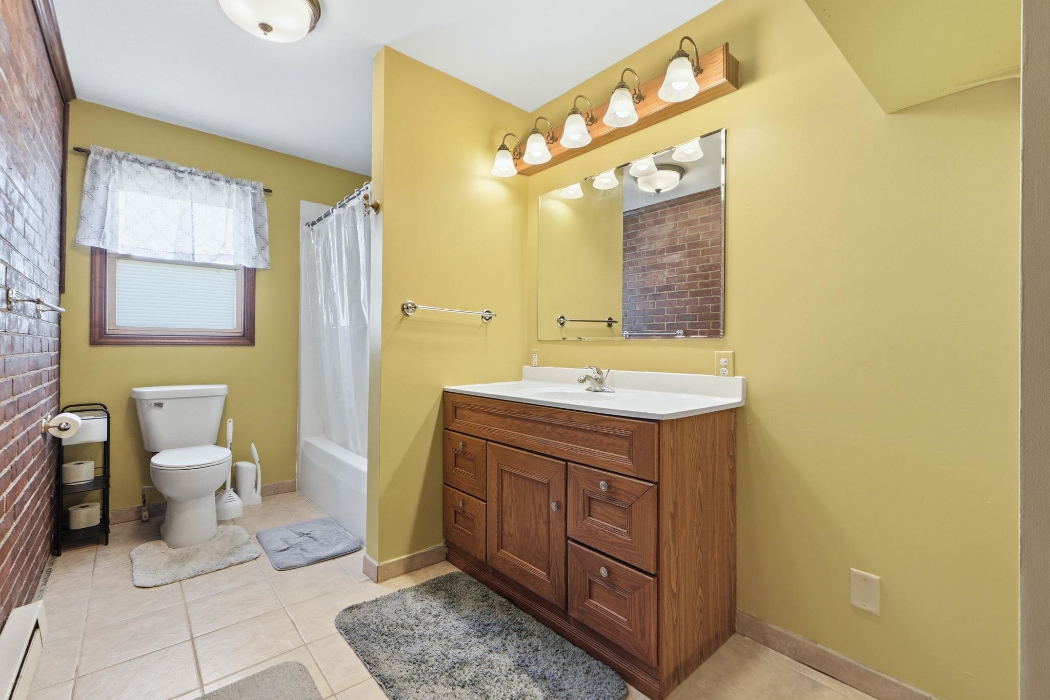 Full bath featuring vanity, light tile patterned flooring, a baseboard radiator, and shower / bath combo