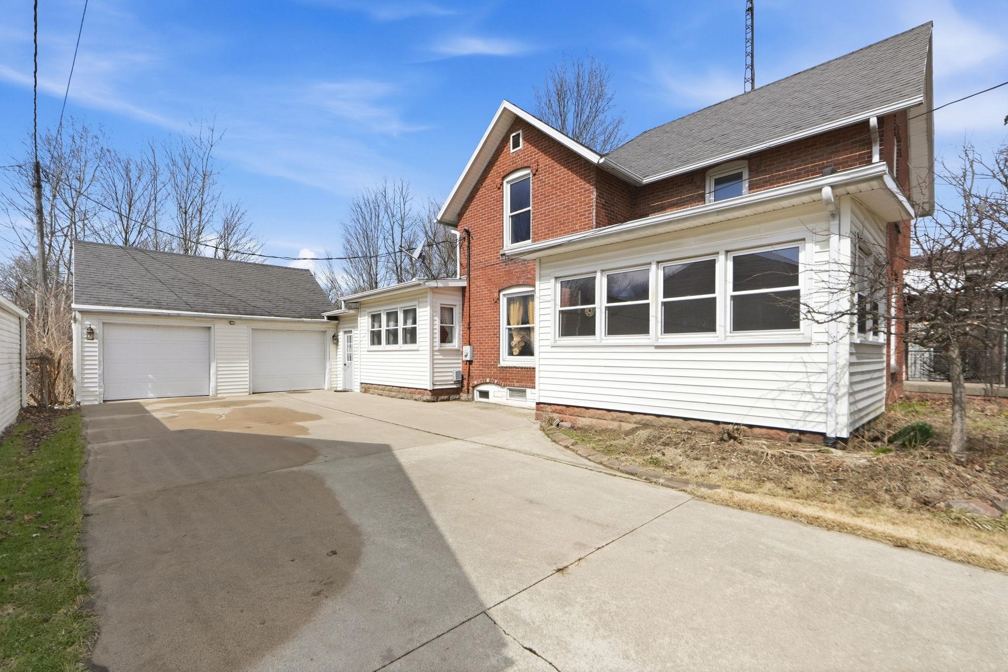 Traditional home with an outbuilding, concrete driveway, brick siding, and roof with shingles