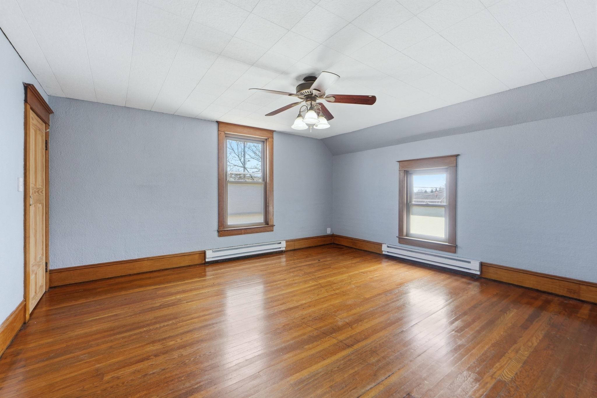 Unfurnished room with hardwood / wood-style flooring, a baseboard heating unit, ceiling fan, and lofted ceiling