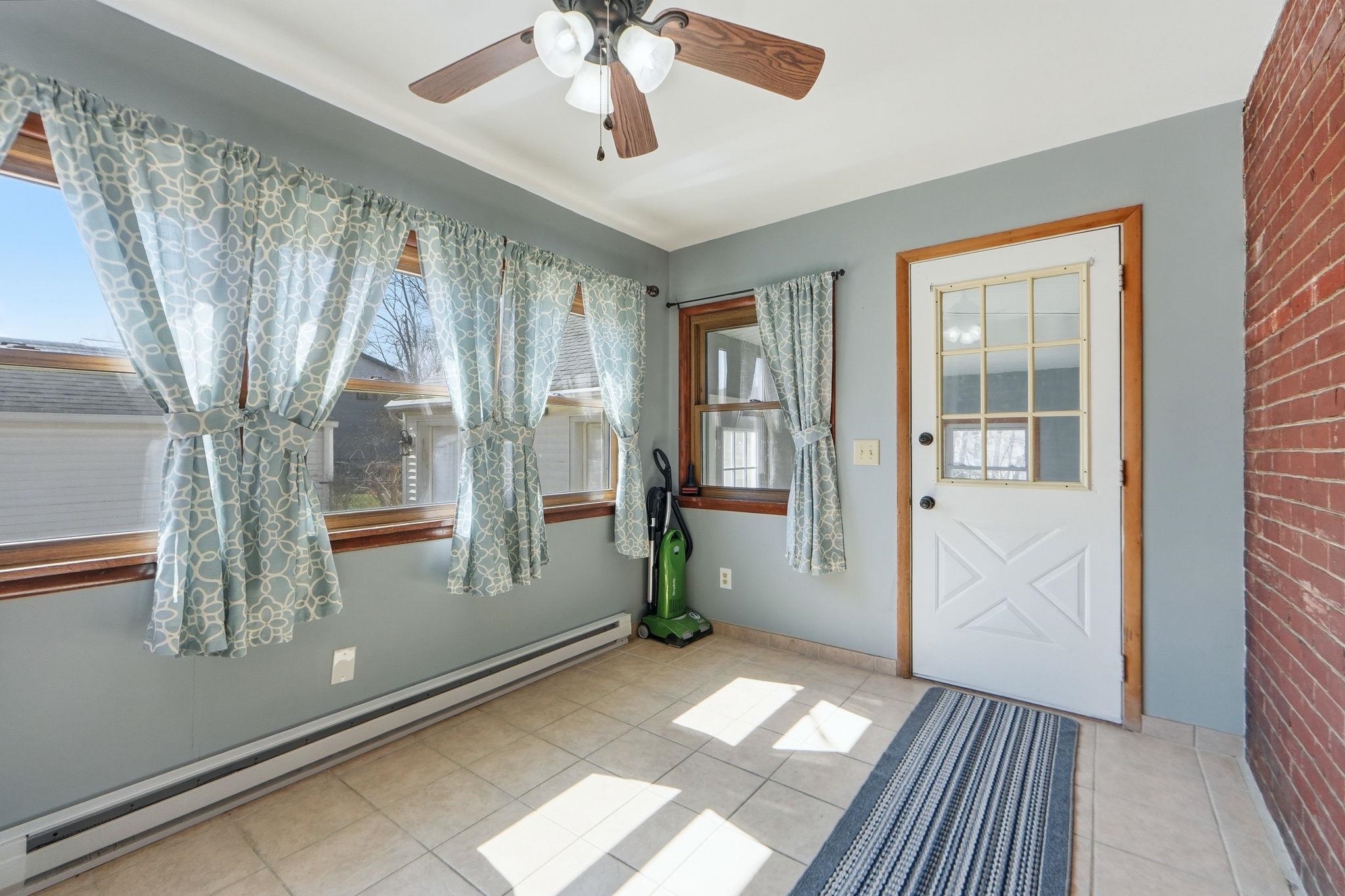Doorway to outside with a baseboard radiator, a ceiling fan, and tile patterned floors