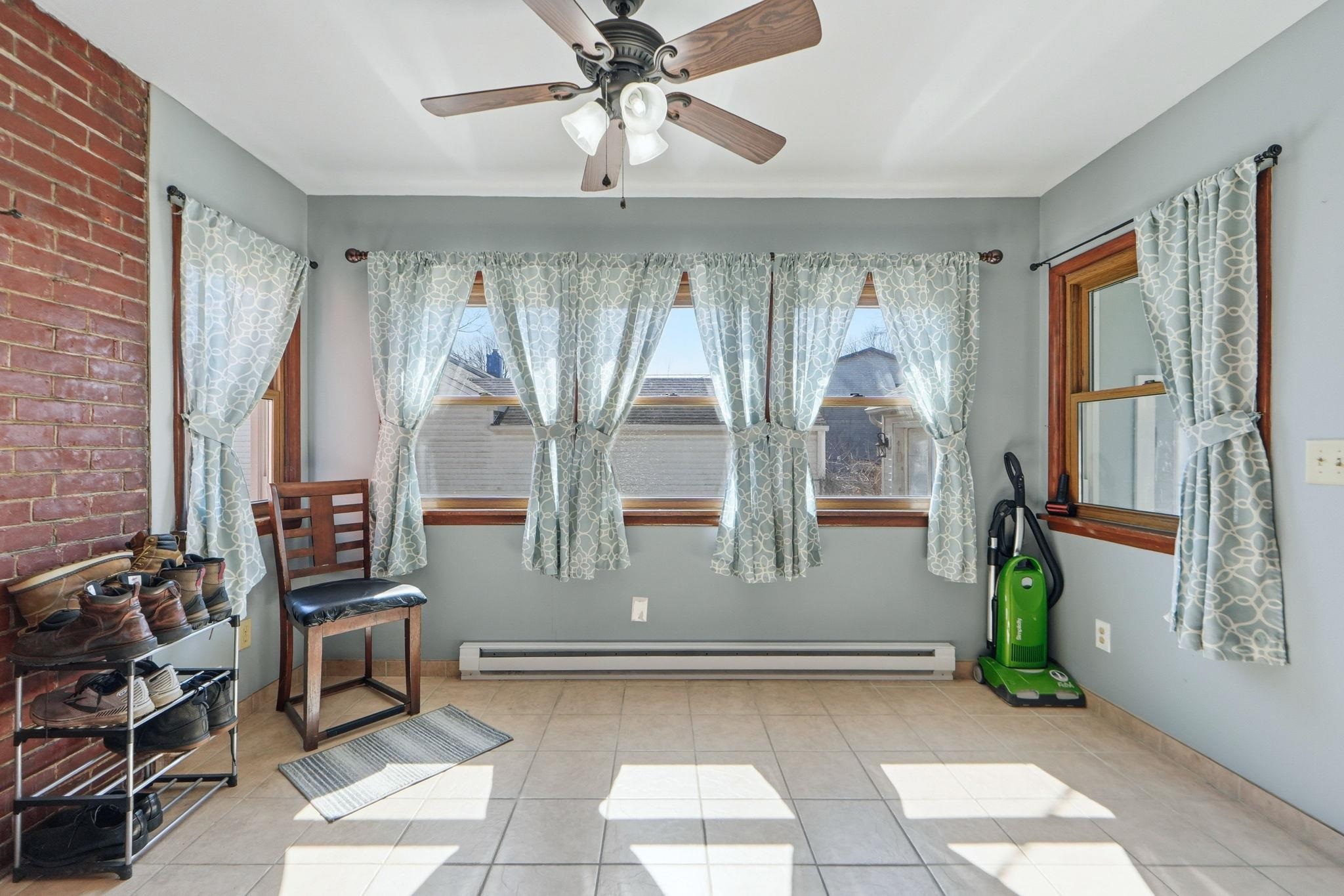Sitting room with a ceiling fan, a baseboard radiator, and light tile patterned flooring