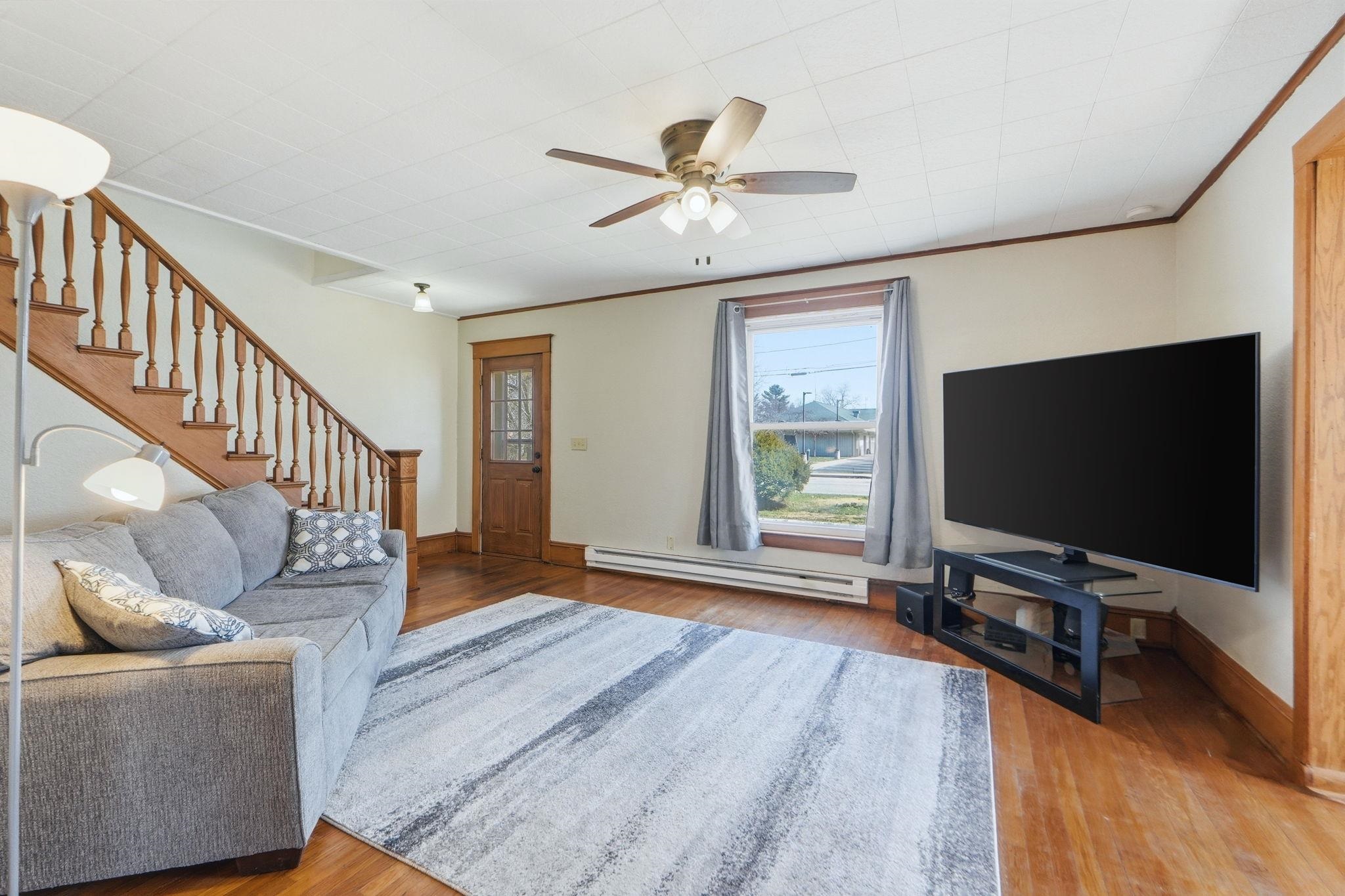Living room featuring a ceiling fan, a baseboard heating unit, and light wood finished floors