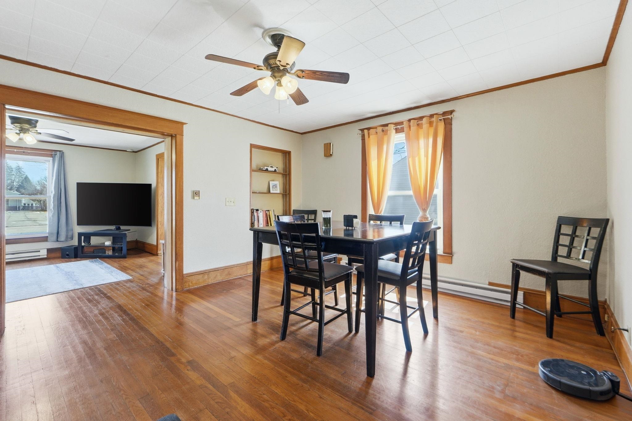 Dining area featuring ceiling fan, hardwood / wood-style flooring, crown molding, and a baseboard heating unit