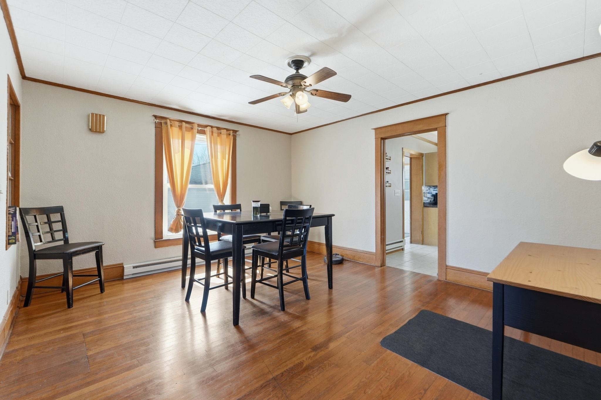 Dining room with hardwood / wood-style floors, a ceiling fan, crown molding, and a baseboard heating unit