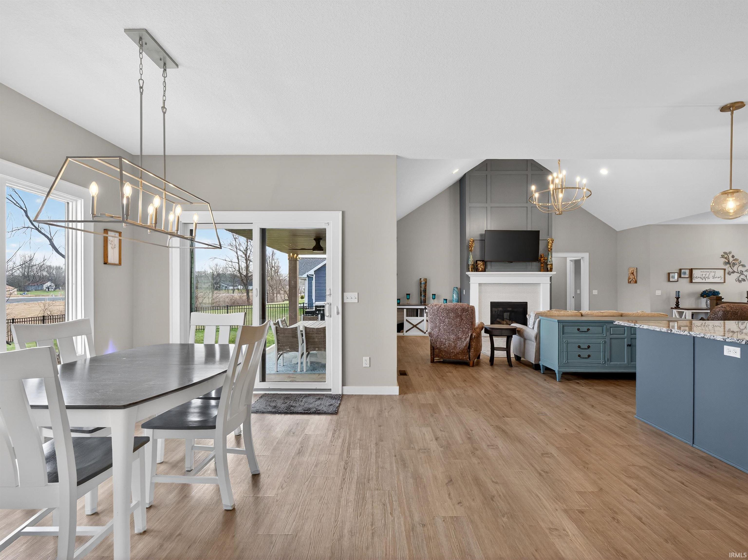 Dining area featuring a chandelier, a fireplace, light wood-style flooring, and lofted ceiling