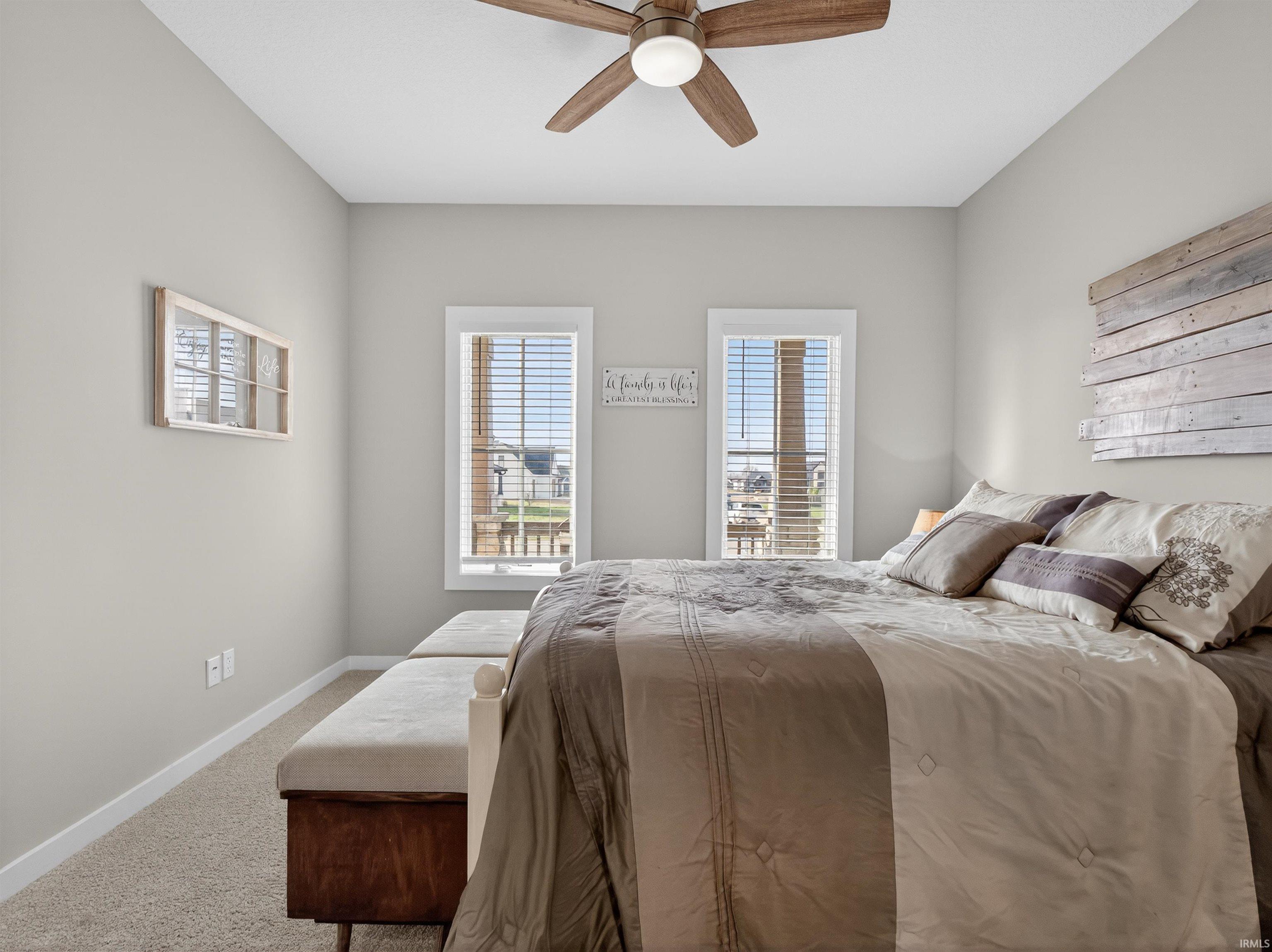 Bedroom featuring carpet flooring, a ceiling fan, and multiple windows