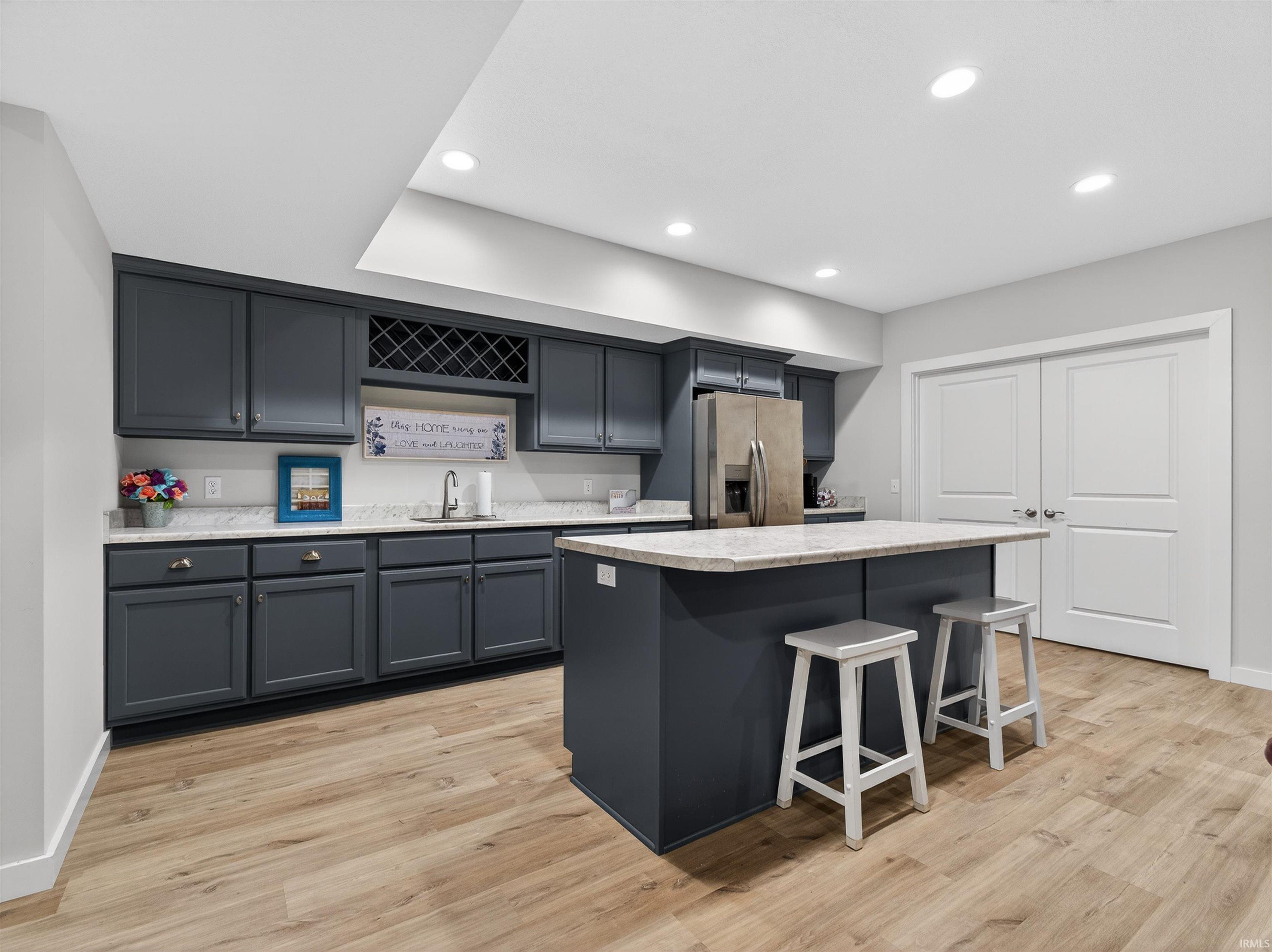 Kitchen featuring a center island, stainless steel fridge, light wood-type flooring, a breakfast bar area, and recessed lighting