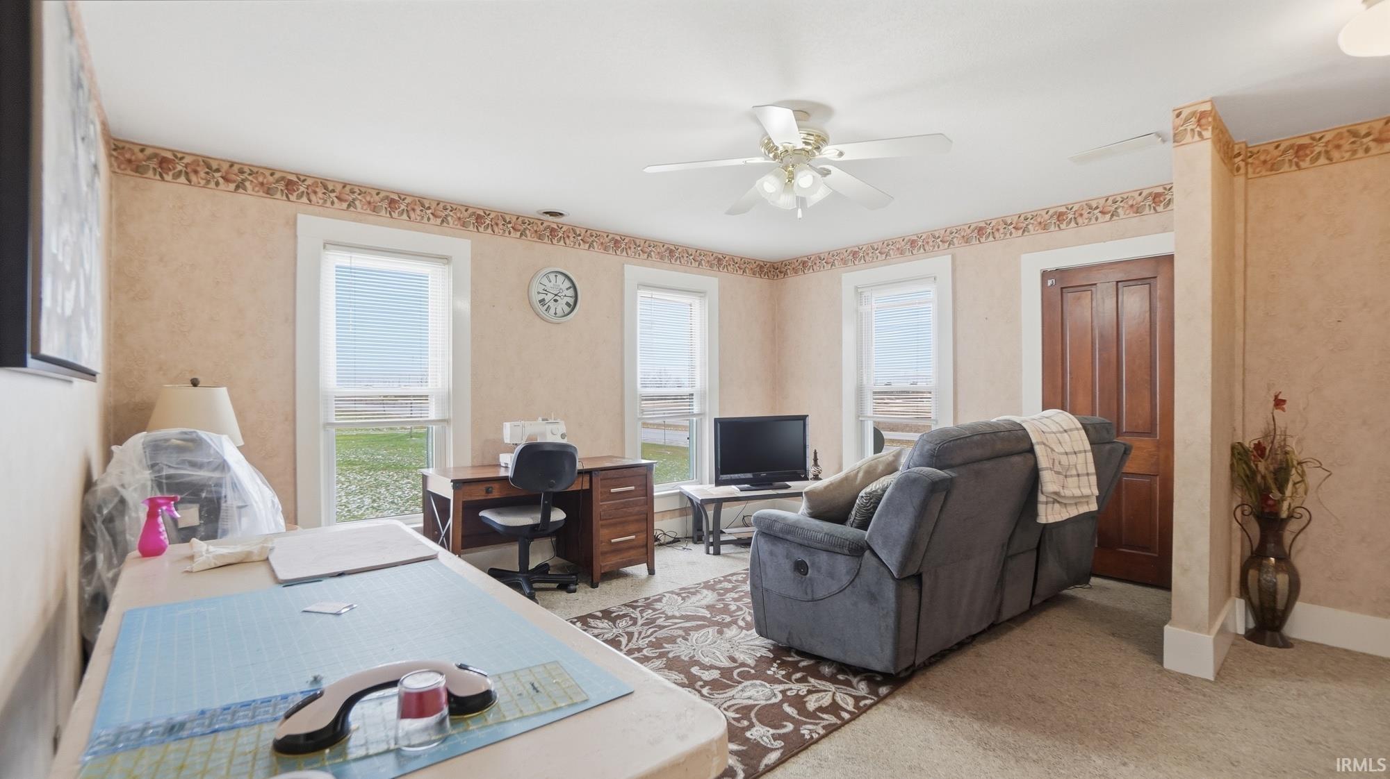 Home office with light carpet and ceiling fan