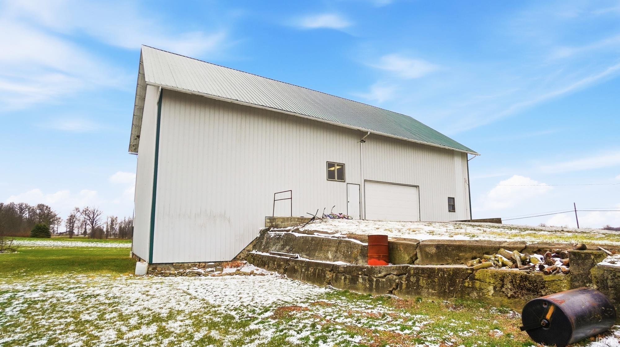 View of home's exterior featuring a metal roof, a detached garage, an outdoor structure, and an outbuilding