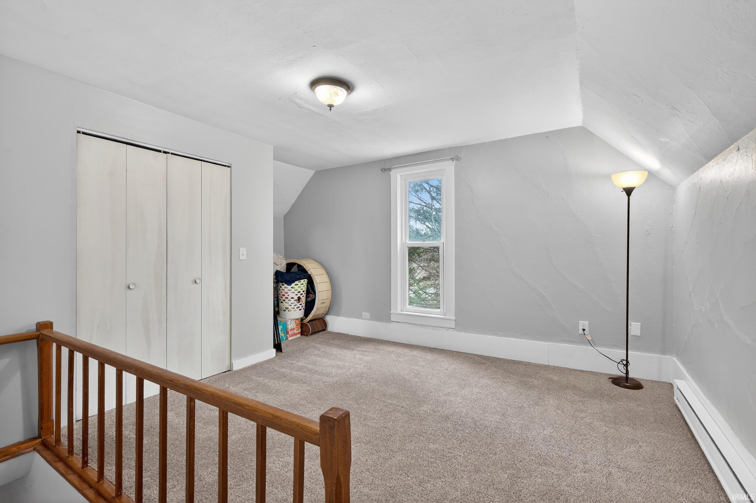 Bonus room with a baseboard radiator and light colored carpet