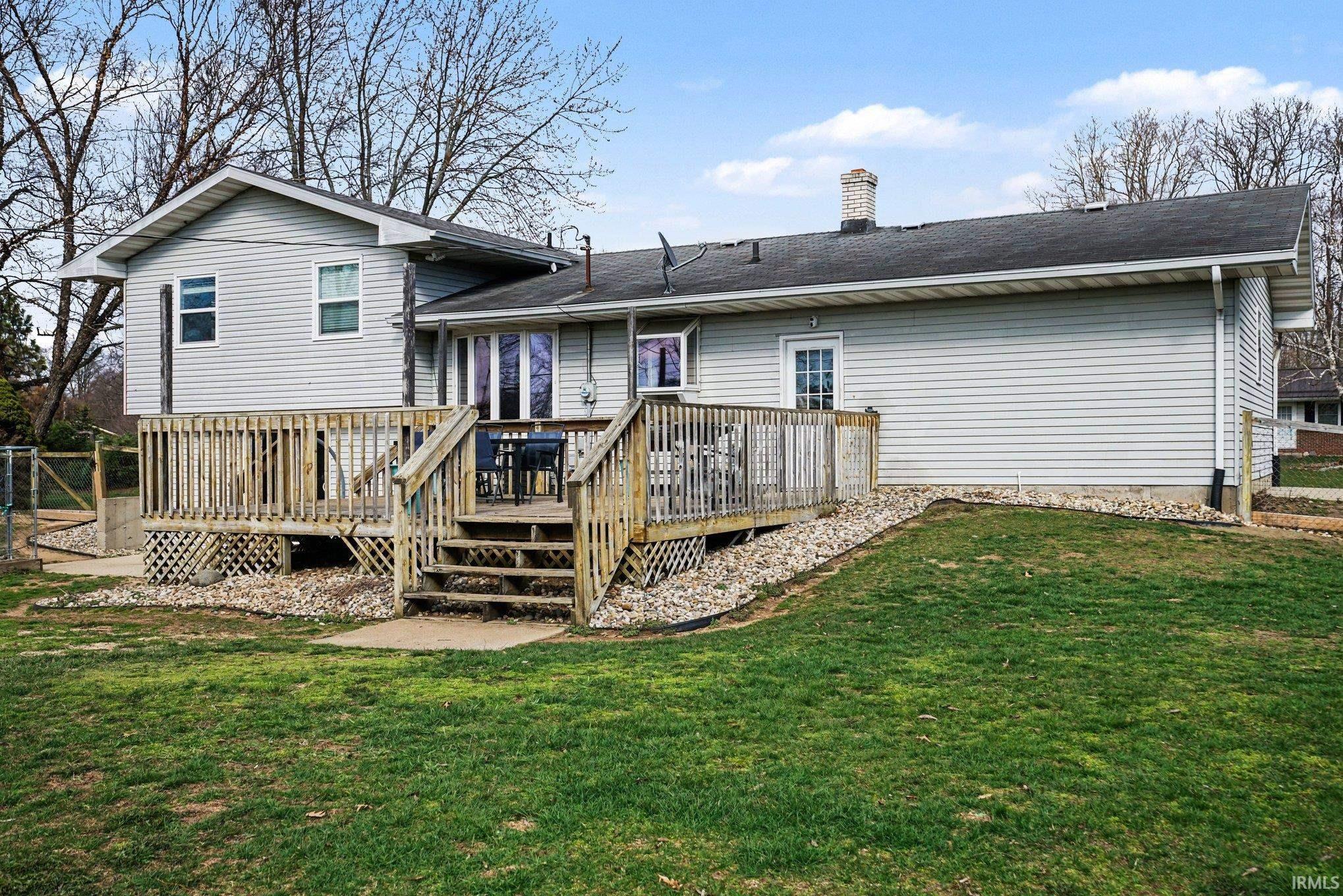Rear view of house featuring a deck, a chimney, and roof with shingles