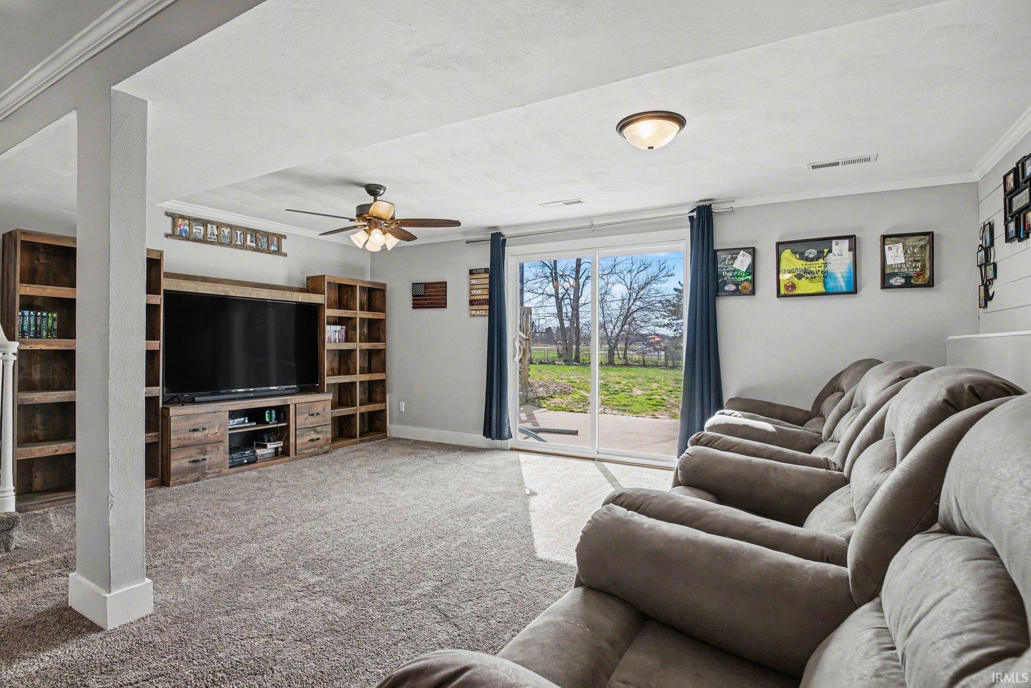 Carpeted living area with crown molding and a ceiling fan