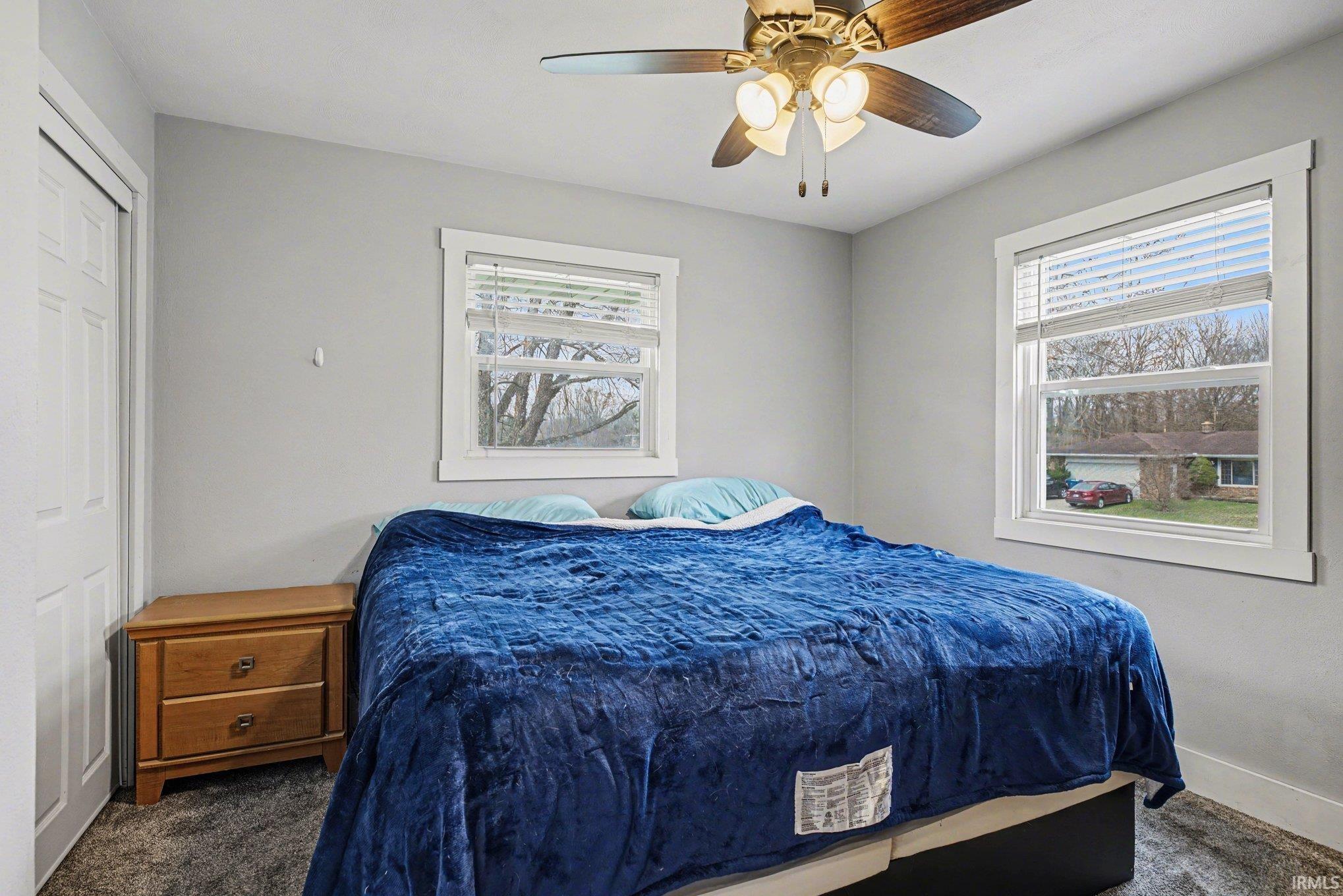 Bedroom featuring ceiling fan, dark colored carpet, and a closet