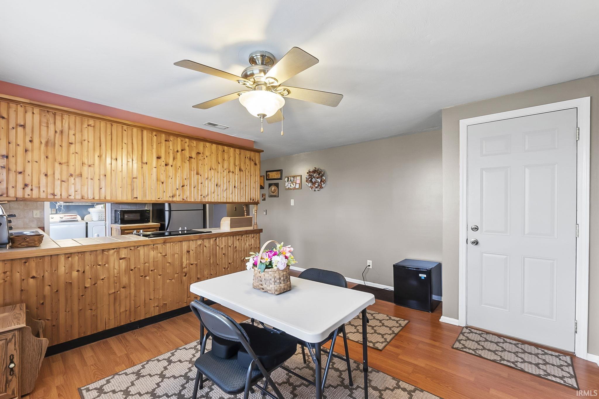 Kitchen with tile counters, ceiling fan, light wood finished floors, black appliances, and washer and dryer