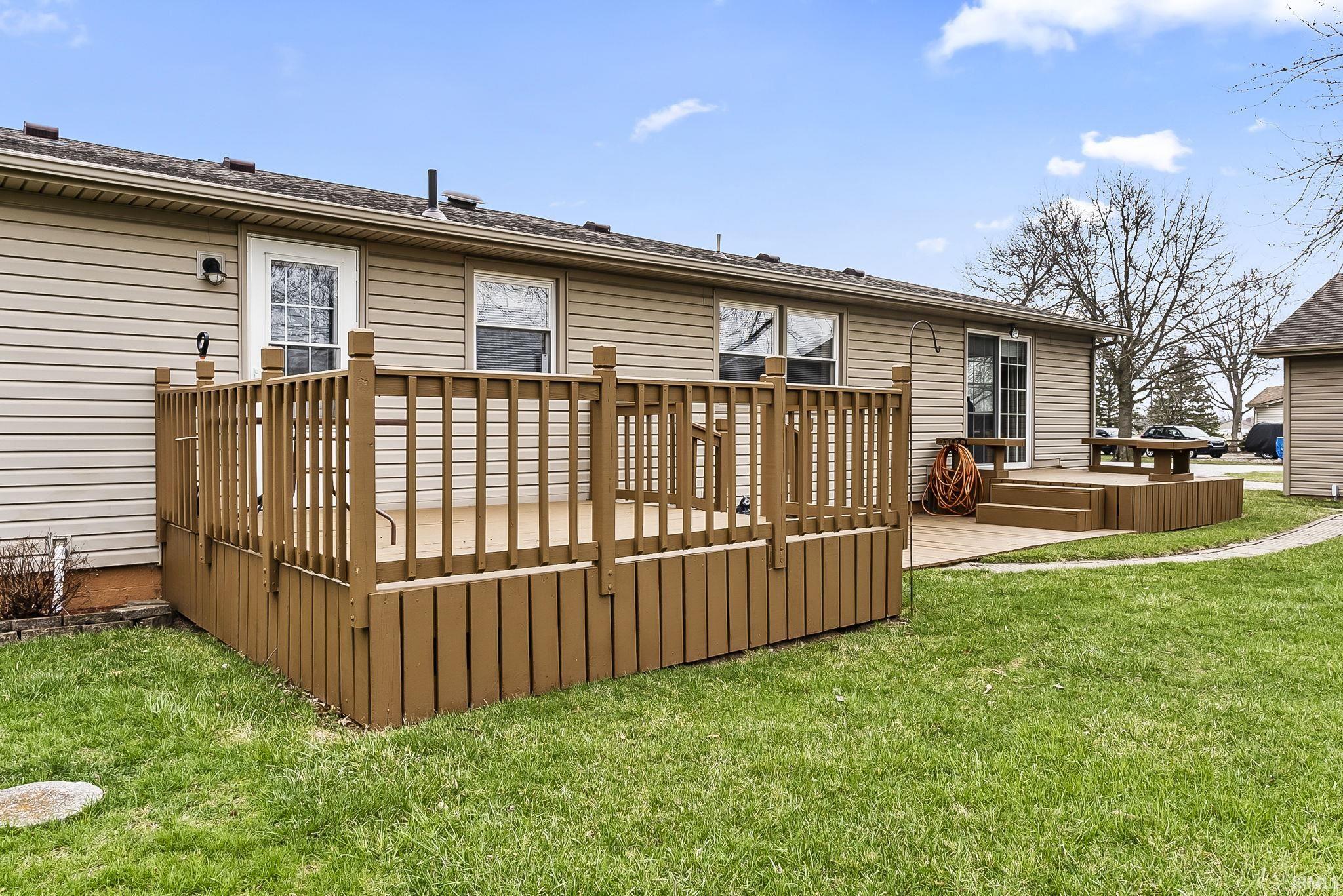 Rear view of property featuring a deck and a yard