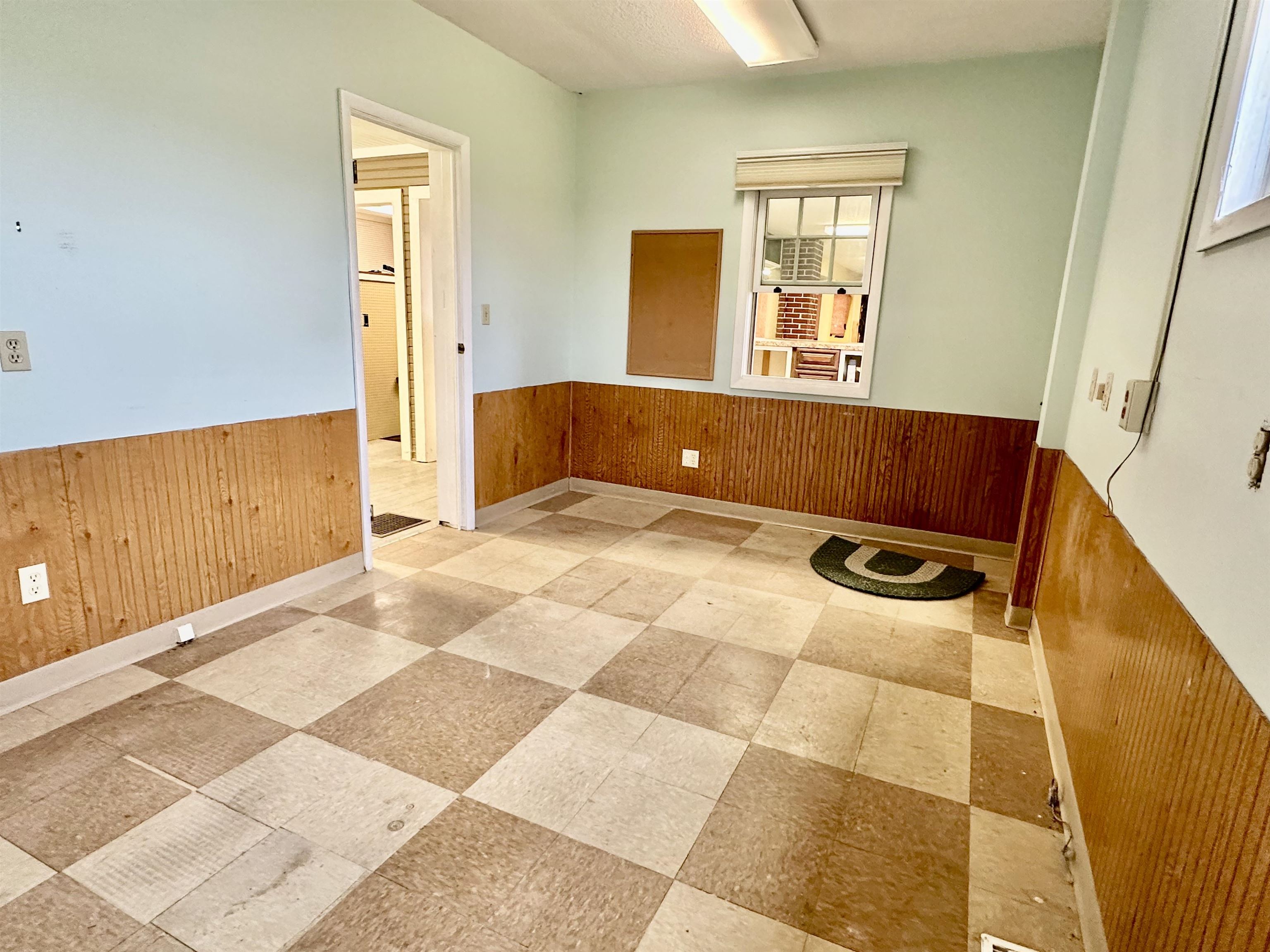 Spare room featuring wooden walls, a wainscoted wall, and light floors