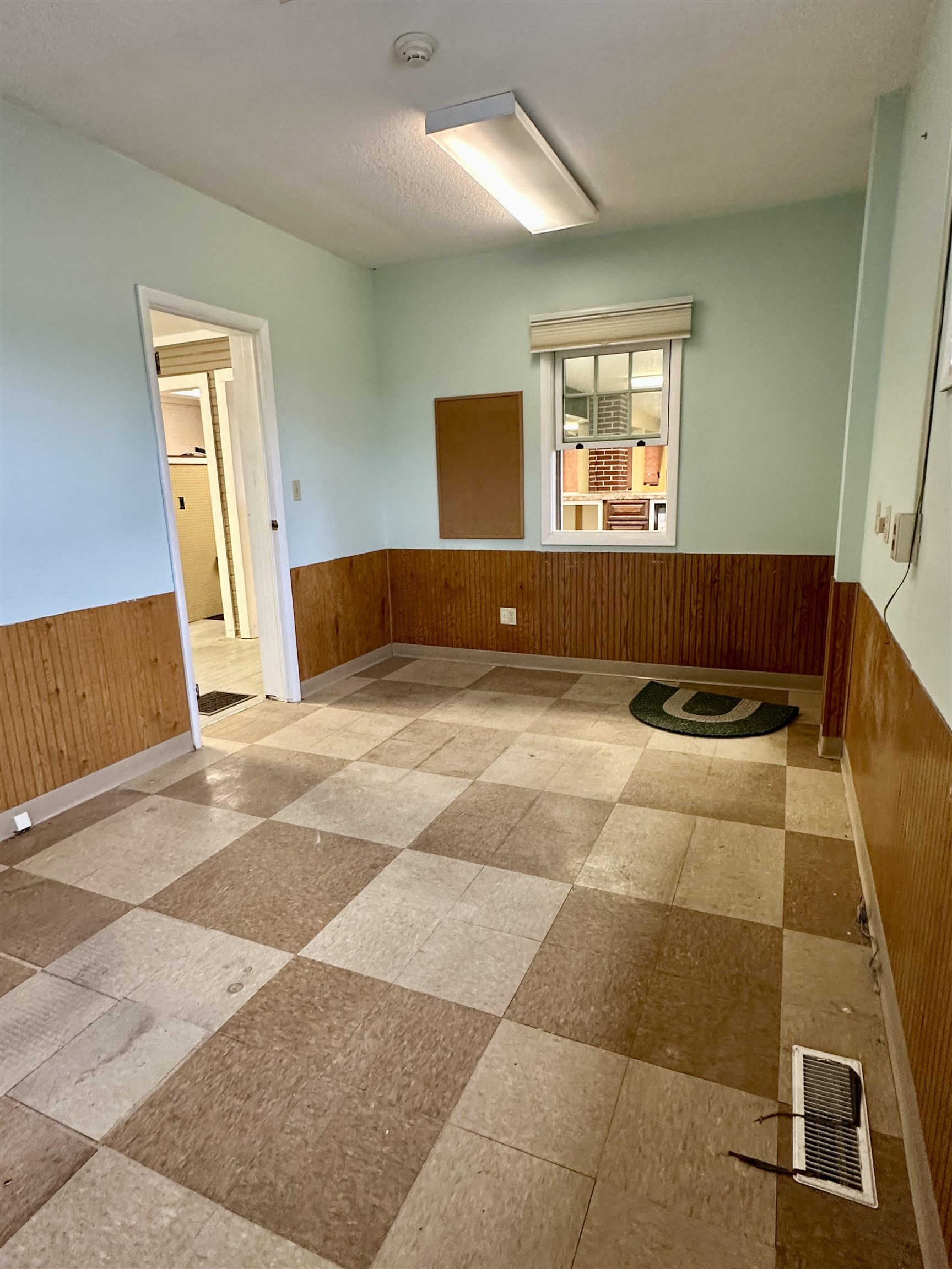 Unfurnished room with wood walls, wainscoting, and light flooring