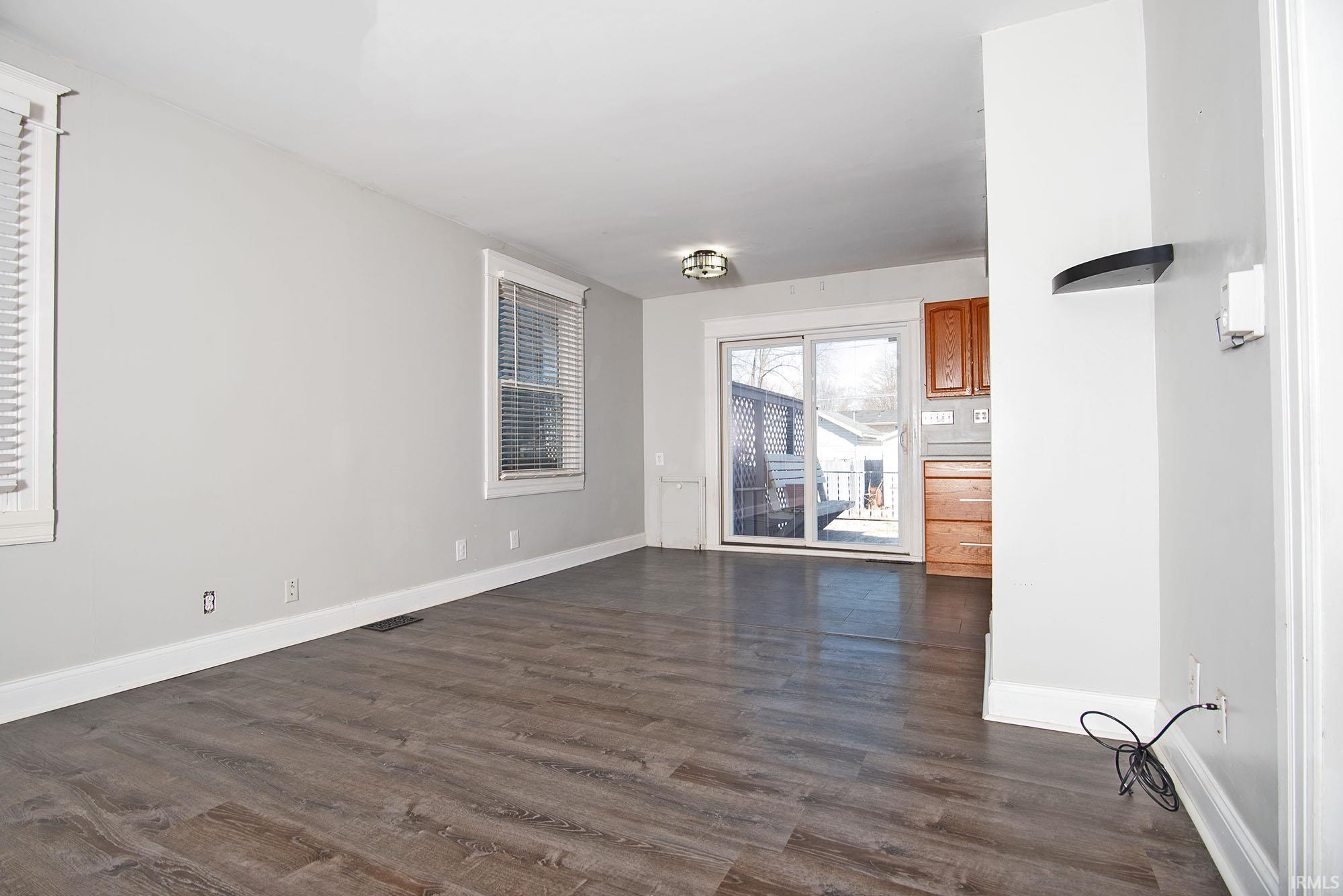 Unfurnished living room with dark wood-type flooring and baseboards