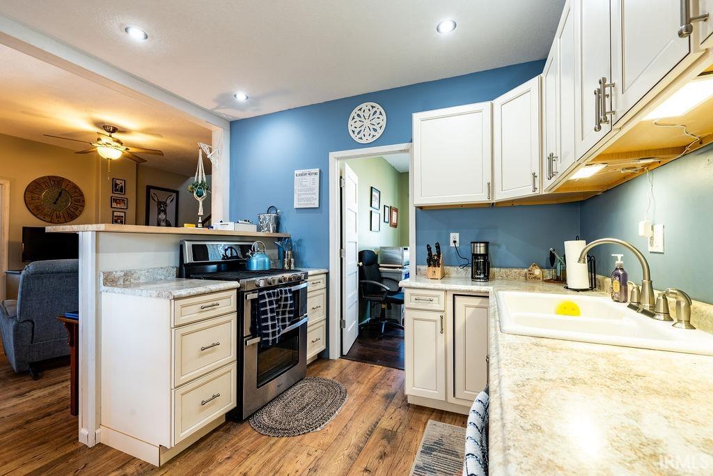 Kitchen featuring range with two ovens, light countertops, light wood-style flooring, a peninsula, and white cabinets