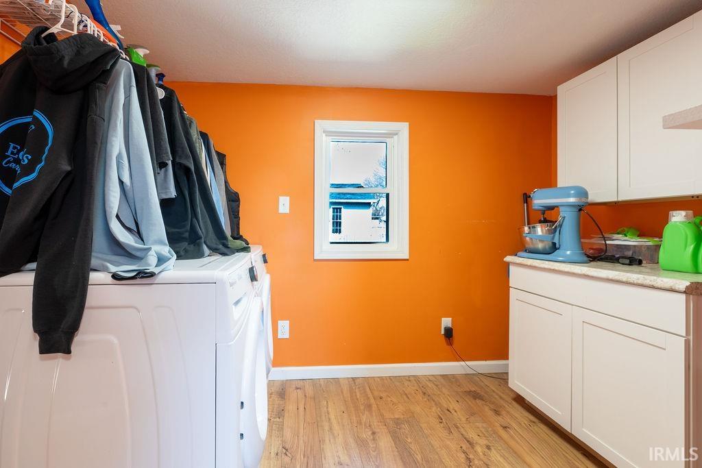 Laundry area with light wood-style flooring, cabinet space, and separate washer and dryer