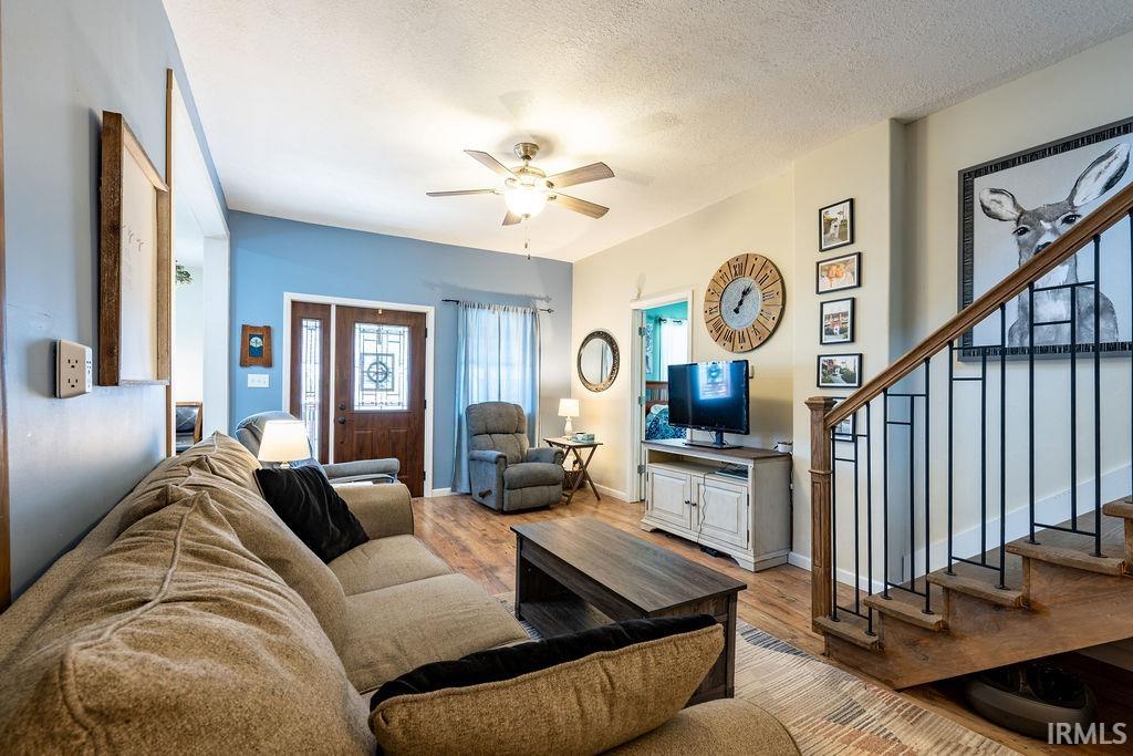 Living area featuring wood finished floors, a ceiling fan, and a textured ceiling