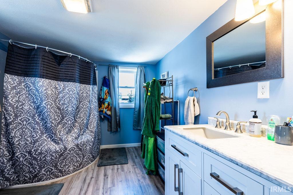 Full bath featuring vanity, light wood-style flooring, and a shower with shower curtain