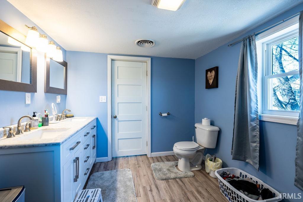 Full bathroom featuring double vanity and light wood-style flooring