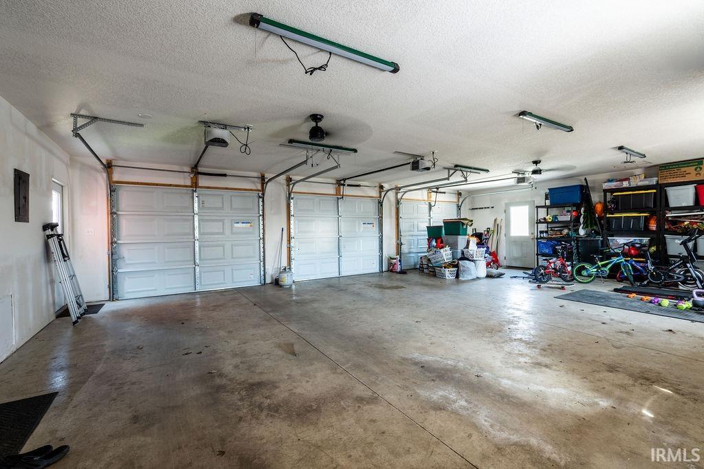 Garage with ceiling fan, electric panel, and a garage door opener