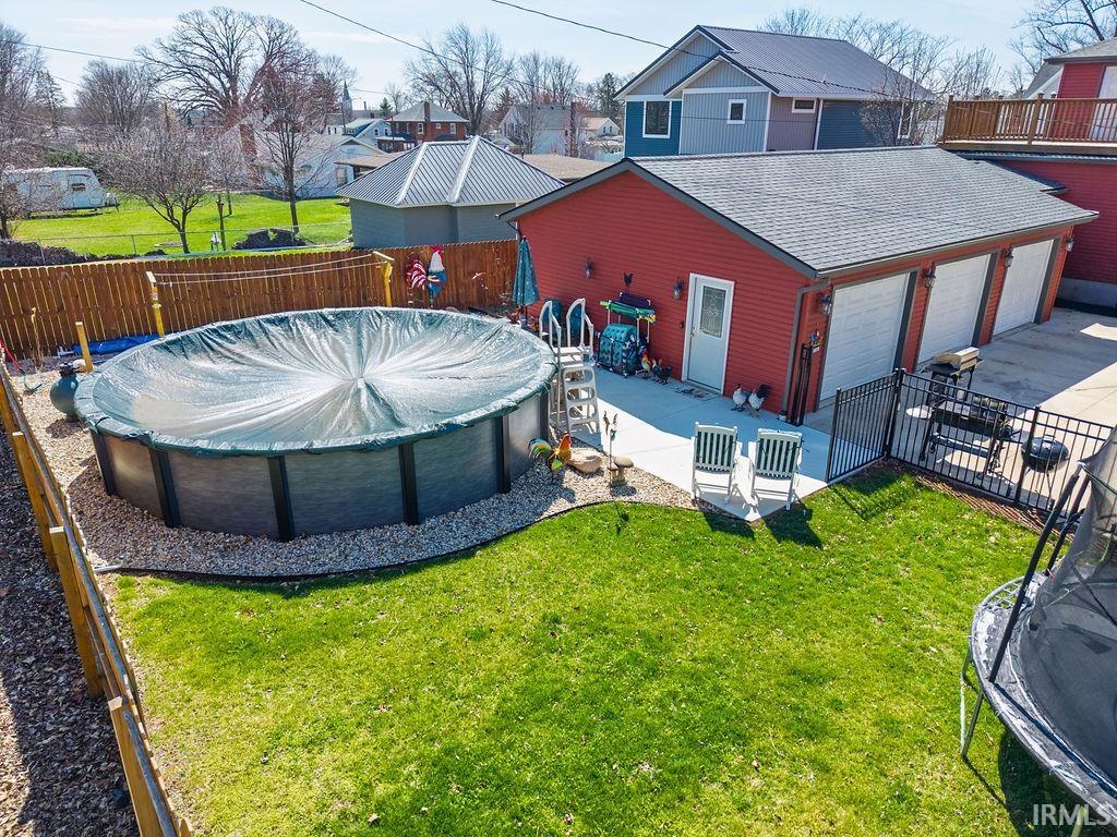 Fenced backyard with a patio area, a trampoline, a garage, and a residential view