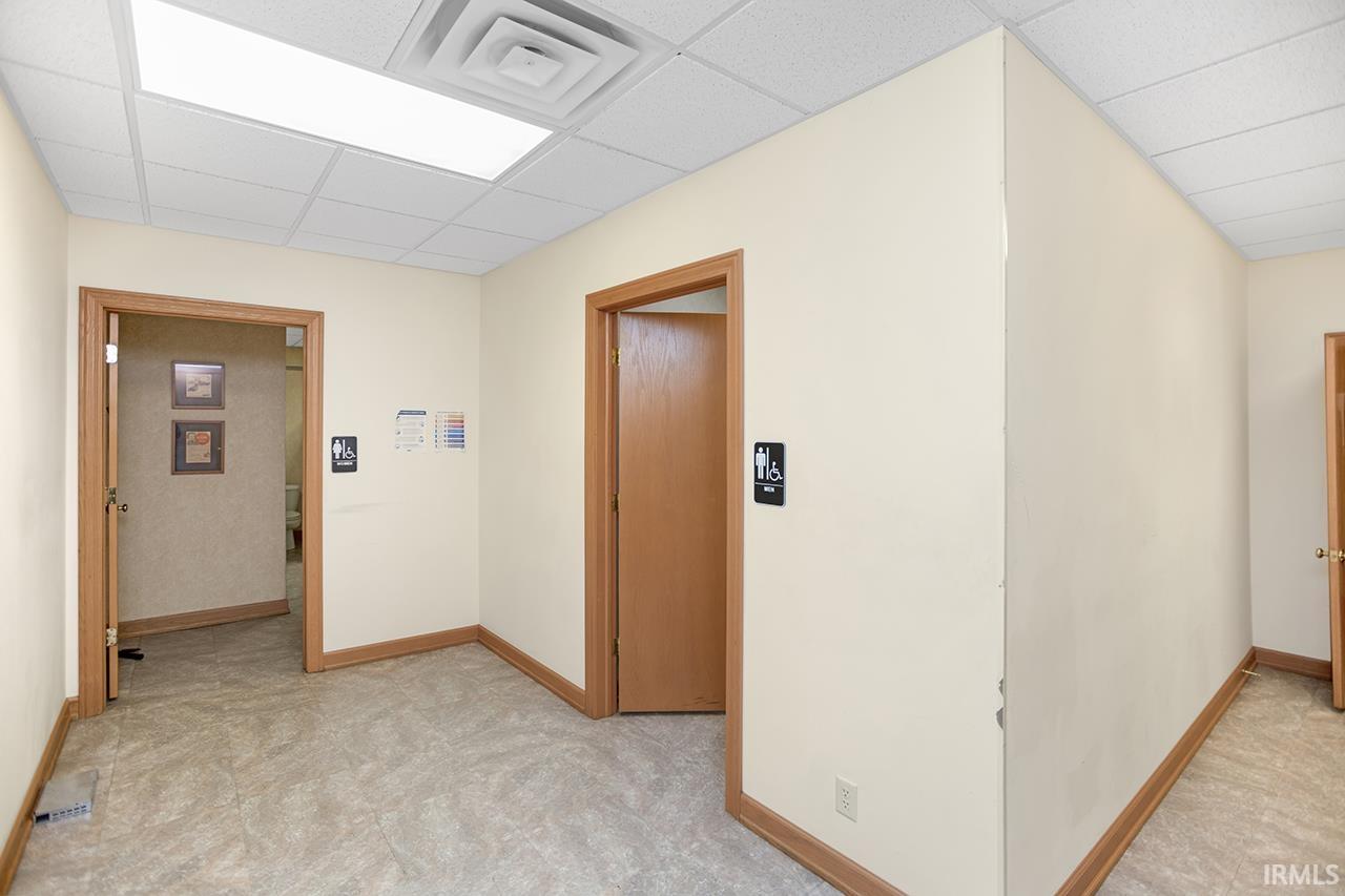 Hallway with a paneled ceiling and light carpet