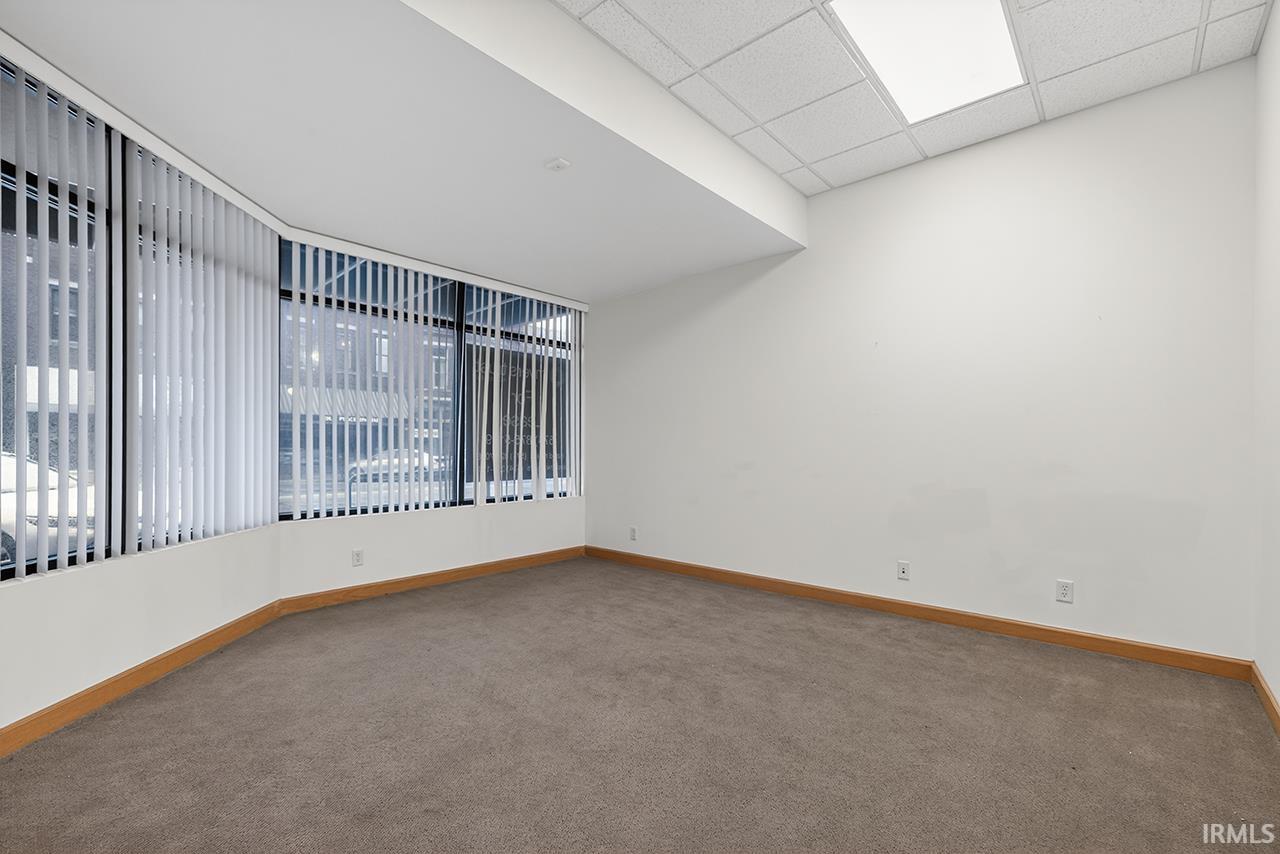 Carpeted spare room with baseboards and a drop ceiling