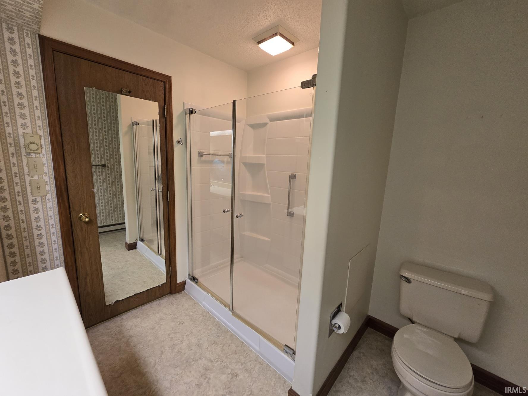 Bathroom featuring a stall shower and a textured ceiling