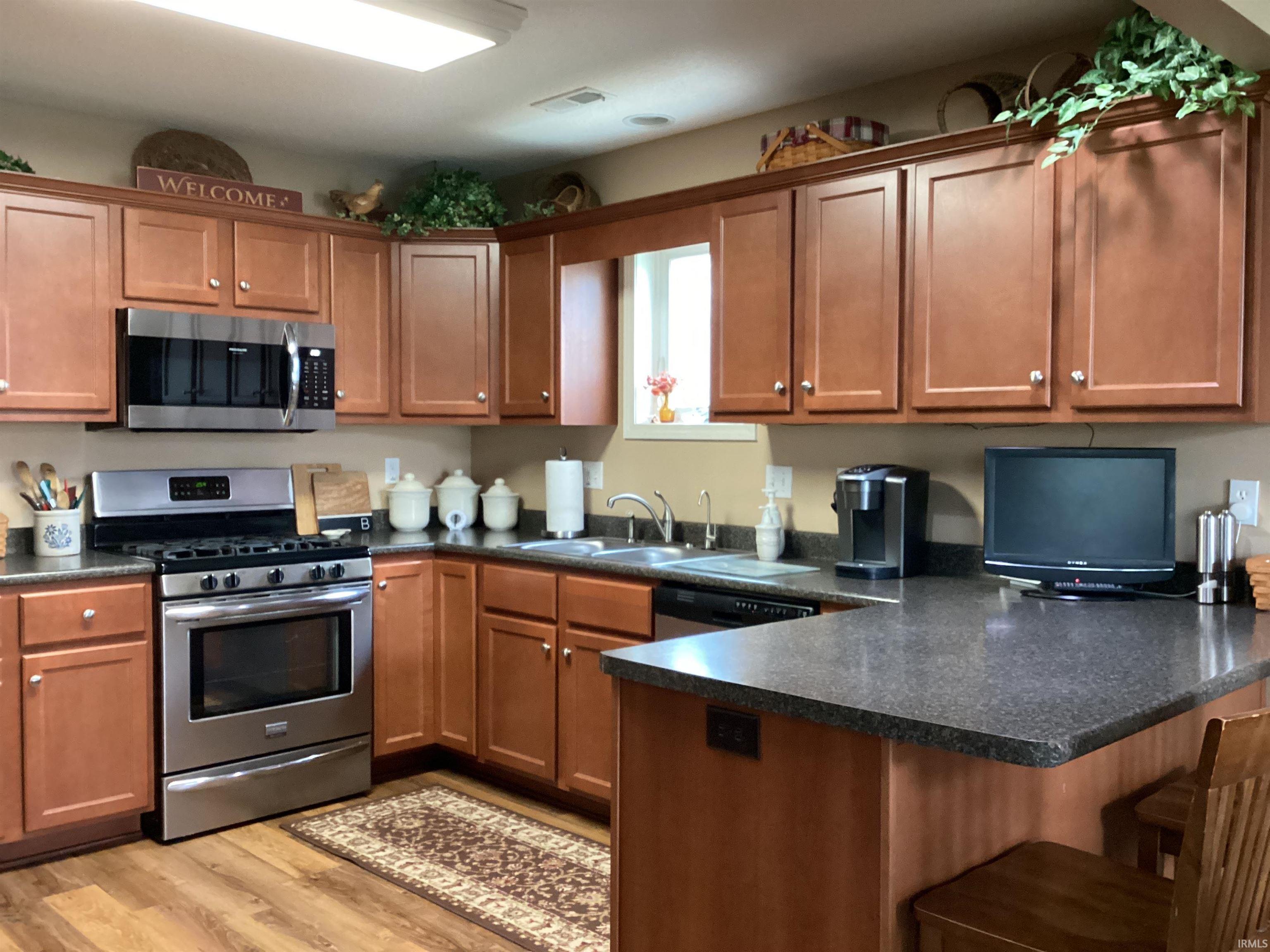 Kitchen featuring dark countertops, stainless steel appliances, and wood finish cabinetry