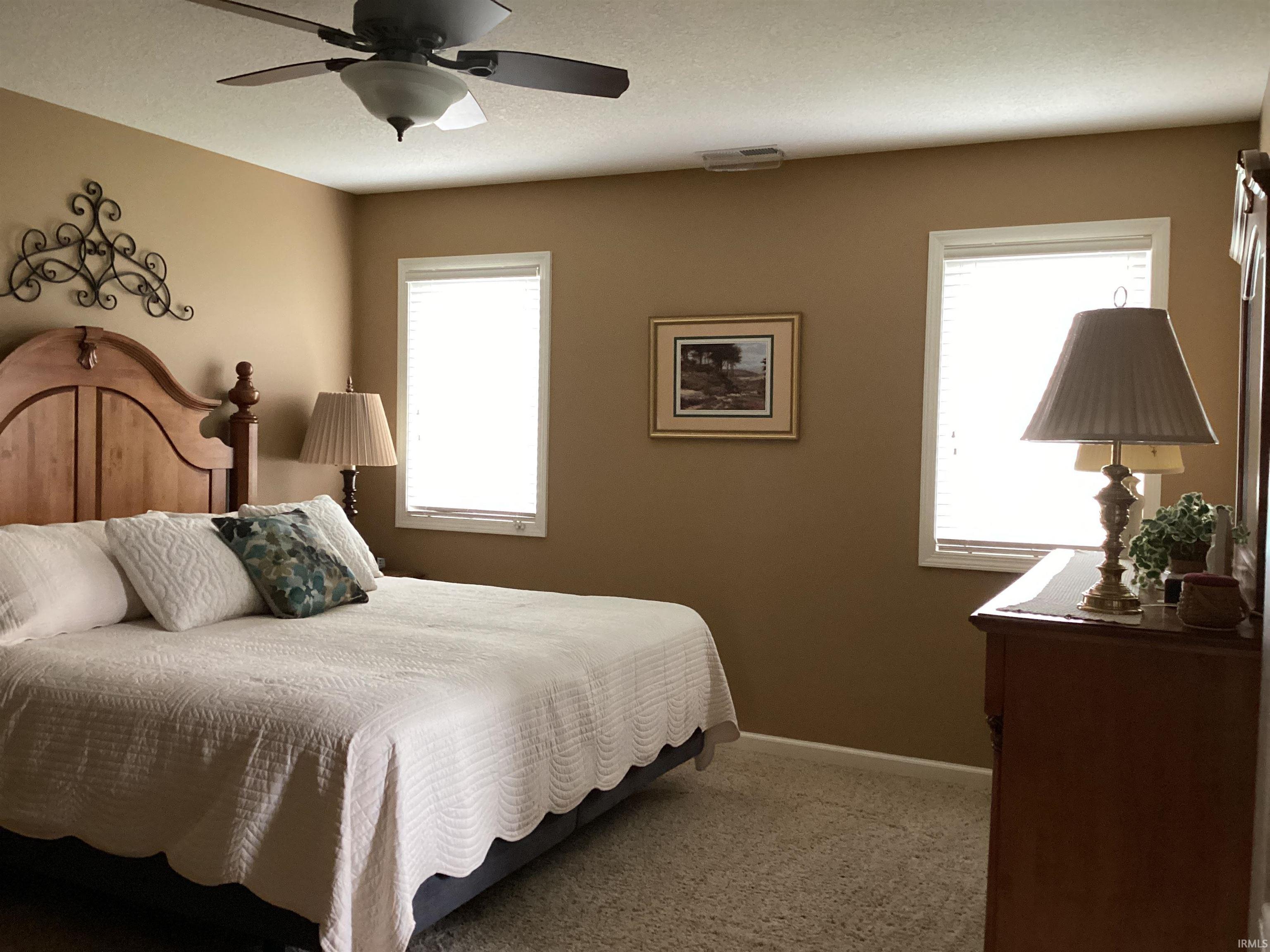 Bedroom with ceiling fan and light colored carpet
