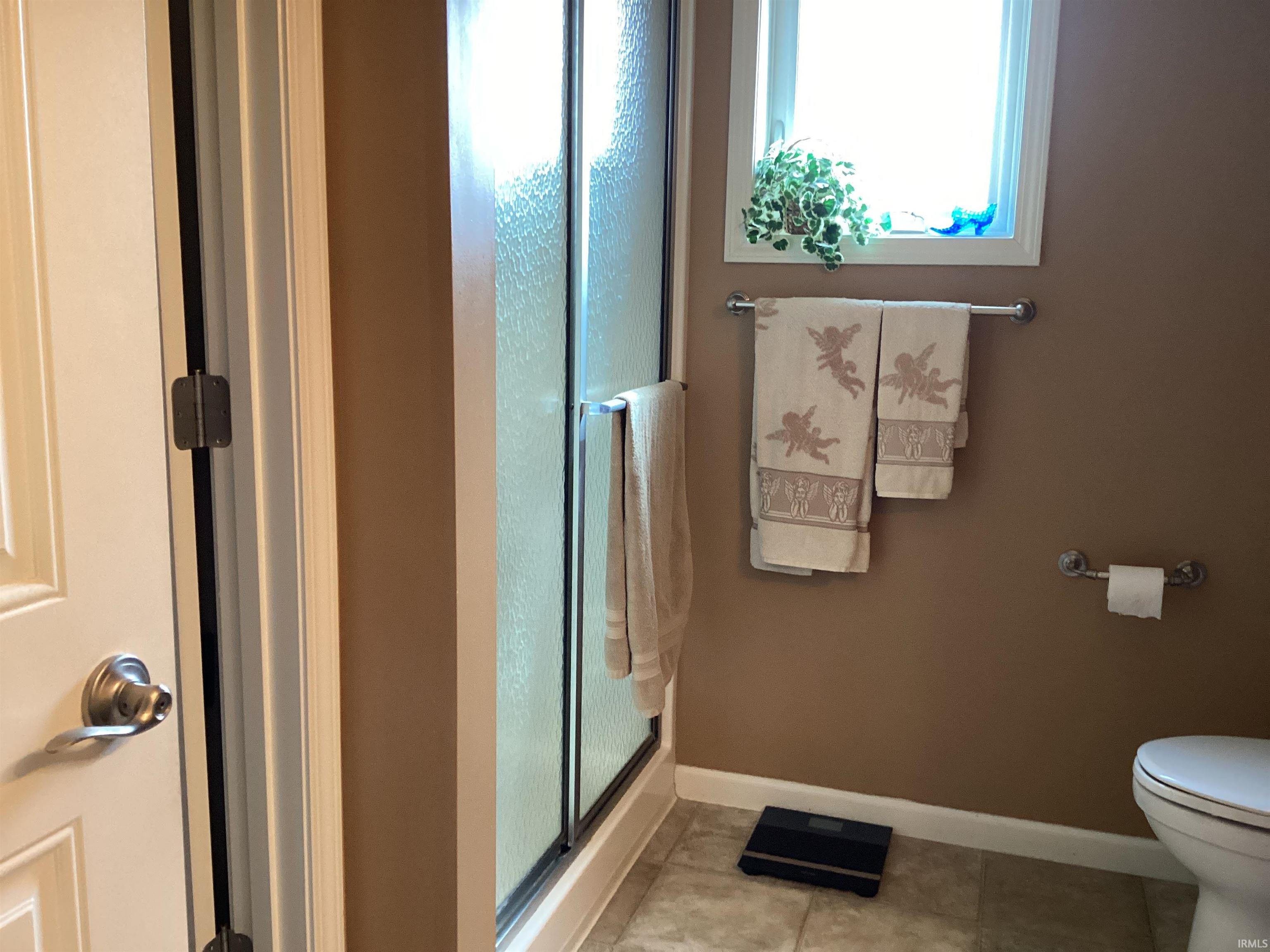 Full bath featuring a shower stall, plenty of natural light, and light tile patterned floors