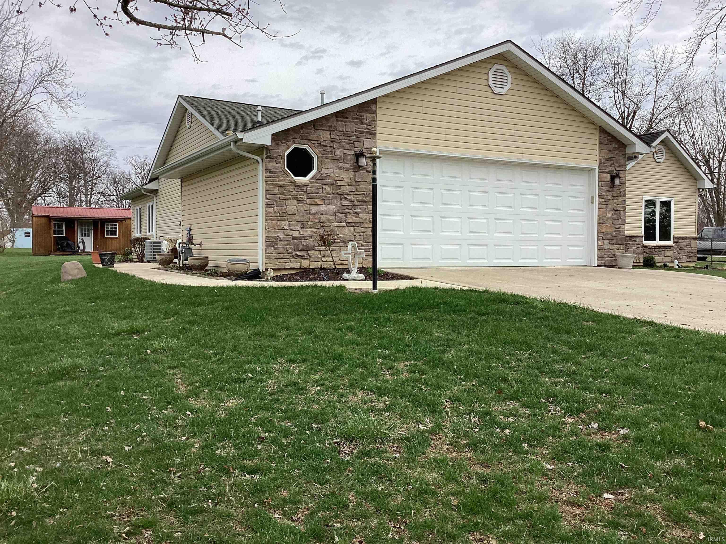 View of home's exterior with stone siding, an attached garage, a yard, and driveway