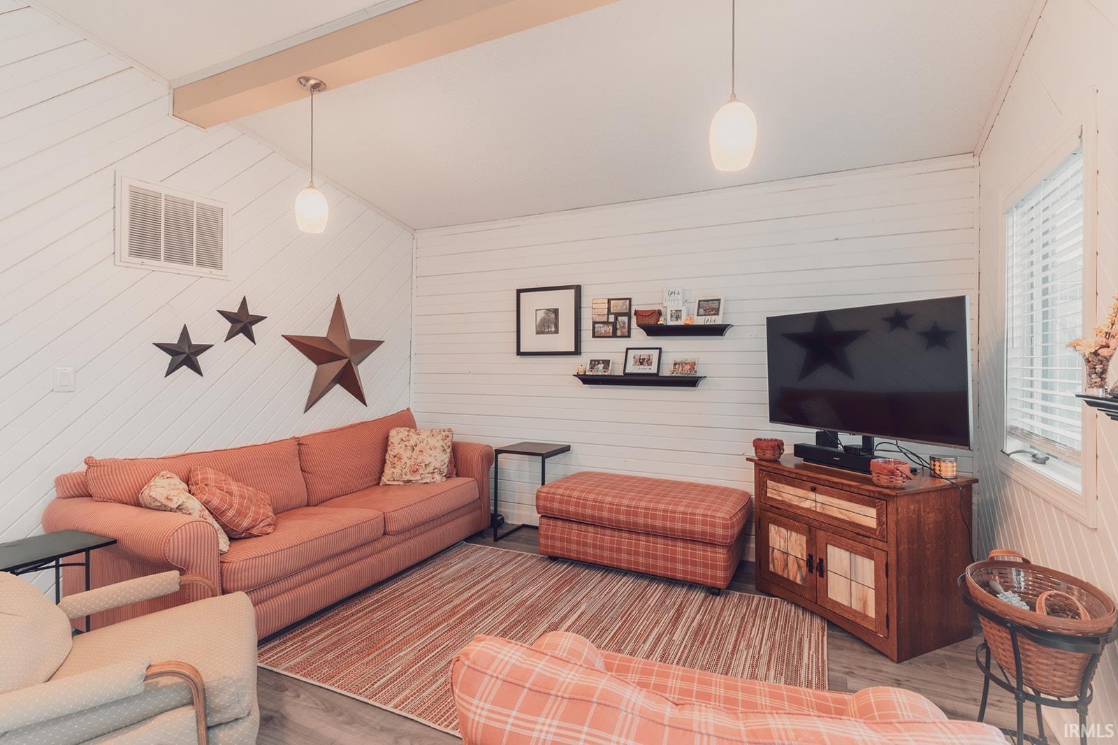 Living room featuring wood finished floors, vaulted ceiling with beams, and wooden walls