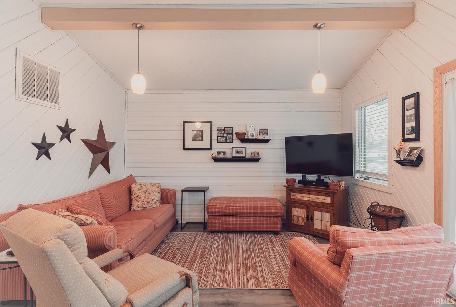 Living area featuring wood walls, wood finished floors, and lofted ceiling with beams