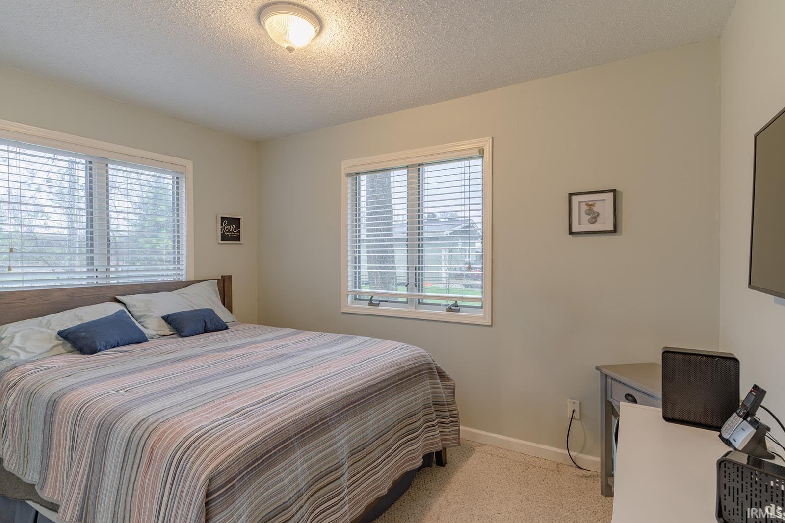 Bedroom featuring a textured ceiling and light carpet
