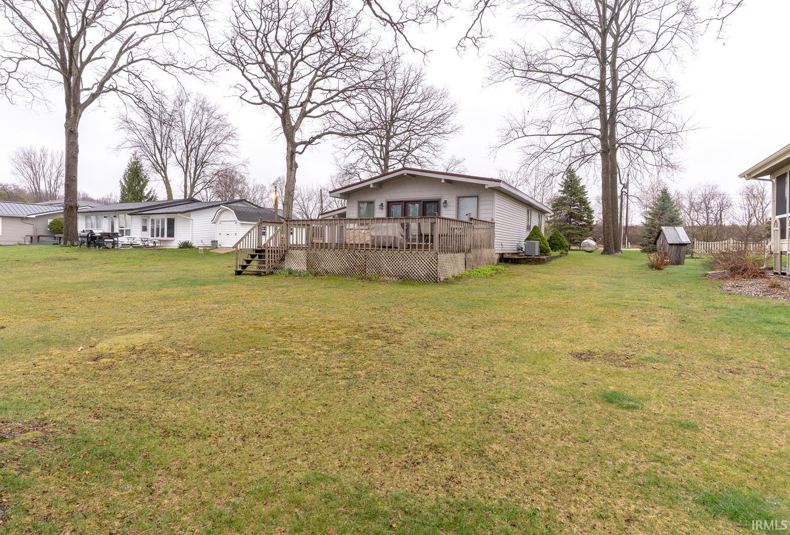 View of green lawn with a wooden deck and a storage unit