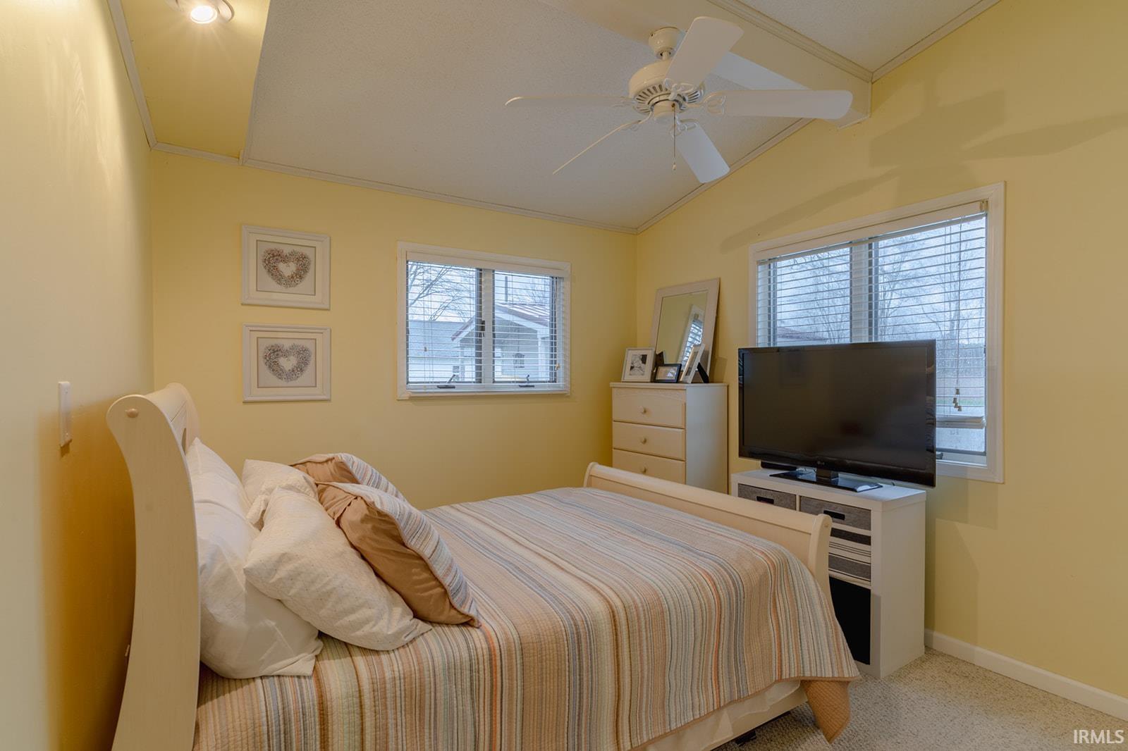 Bedroom featuring ornamental molding, ceiling fan, light carpet, and vaulted ceiling