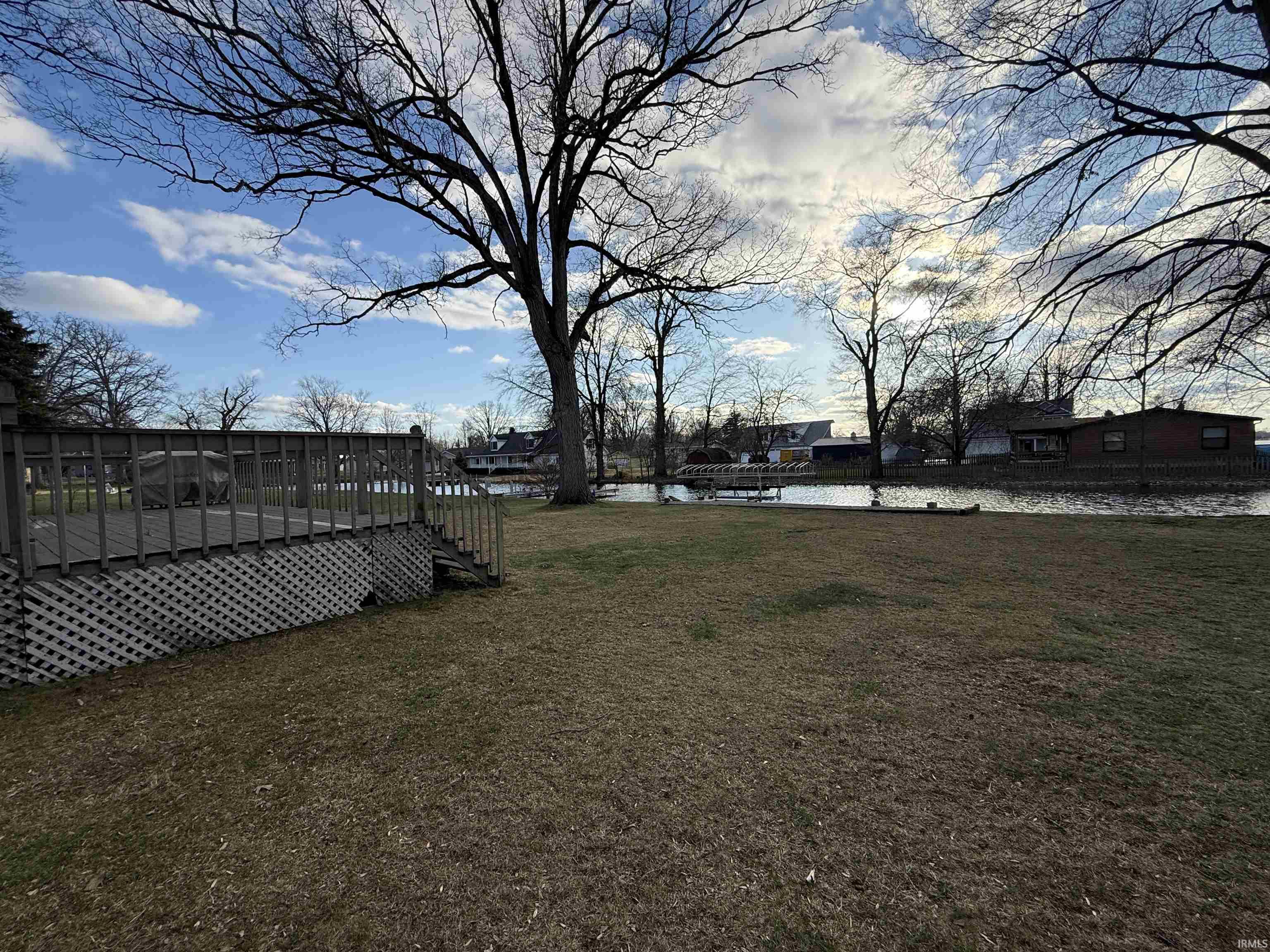 View of grassy yard featuring a deck with water view