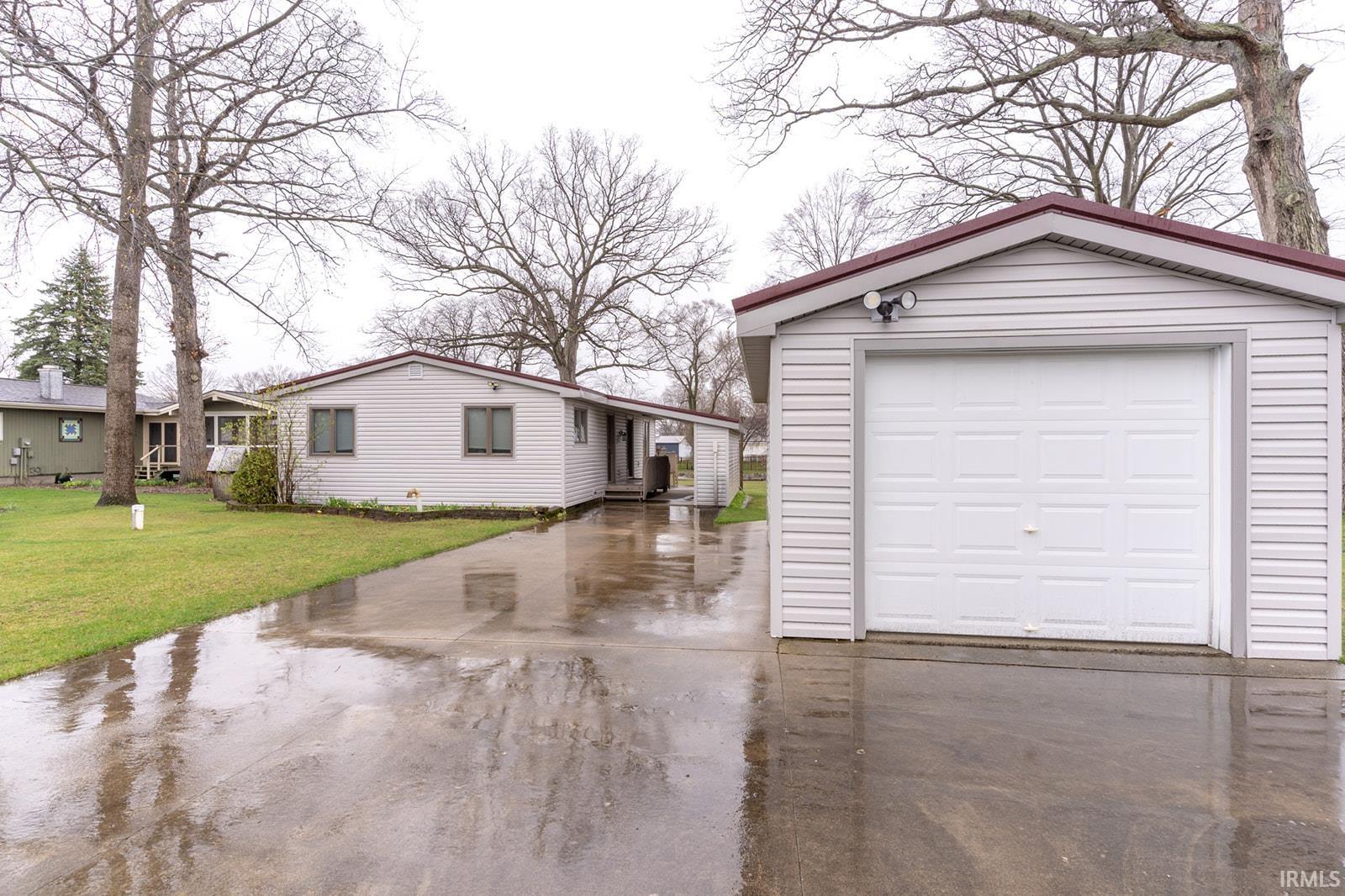 View of back facade with an outbuilding, concrete driveway, and a yard